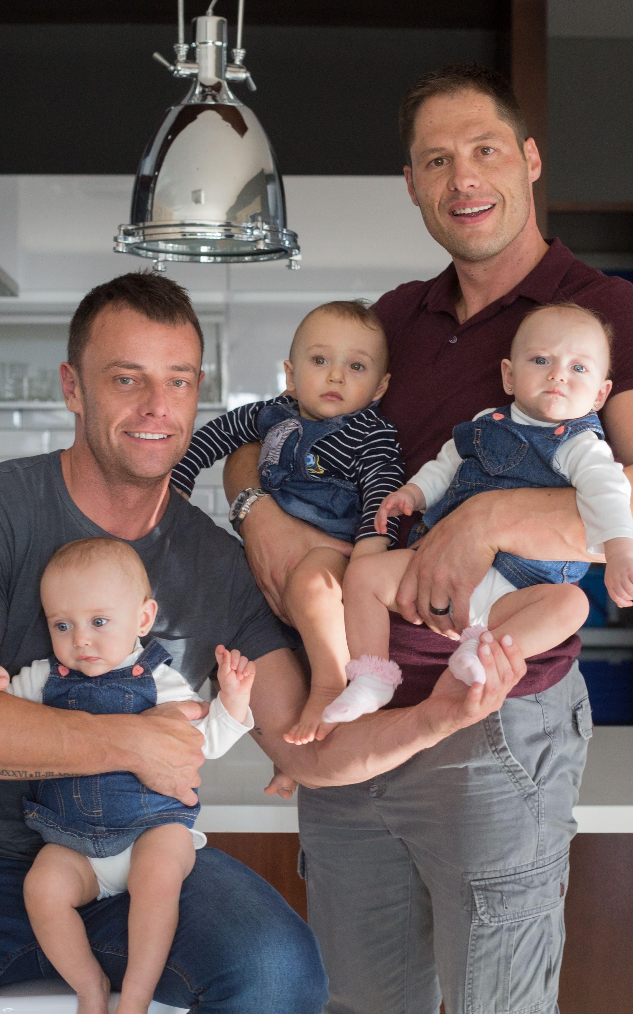 Two white men holding triplets