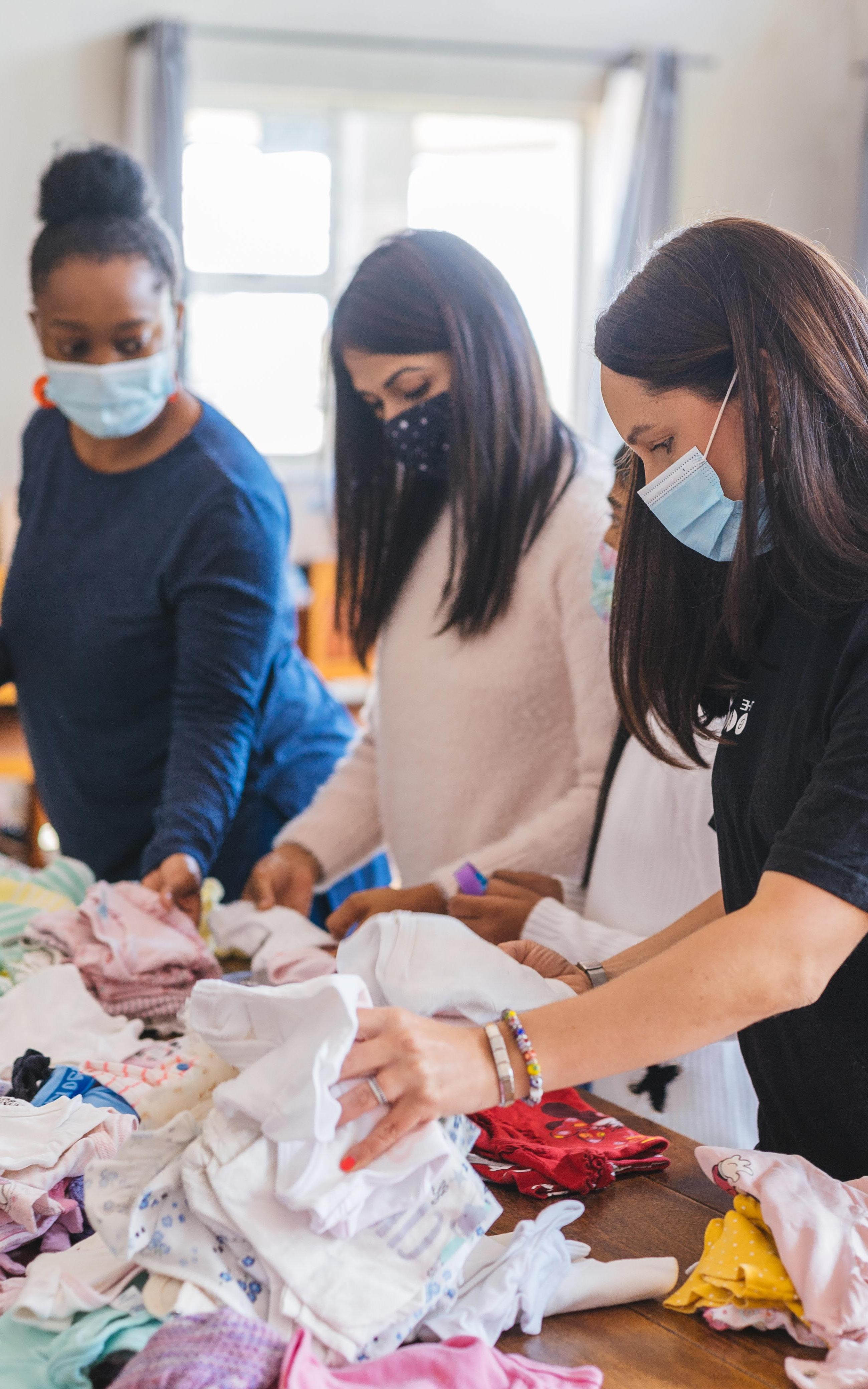 Beautiful News-Women sorting through clothes wearing masks.