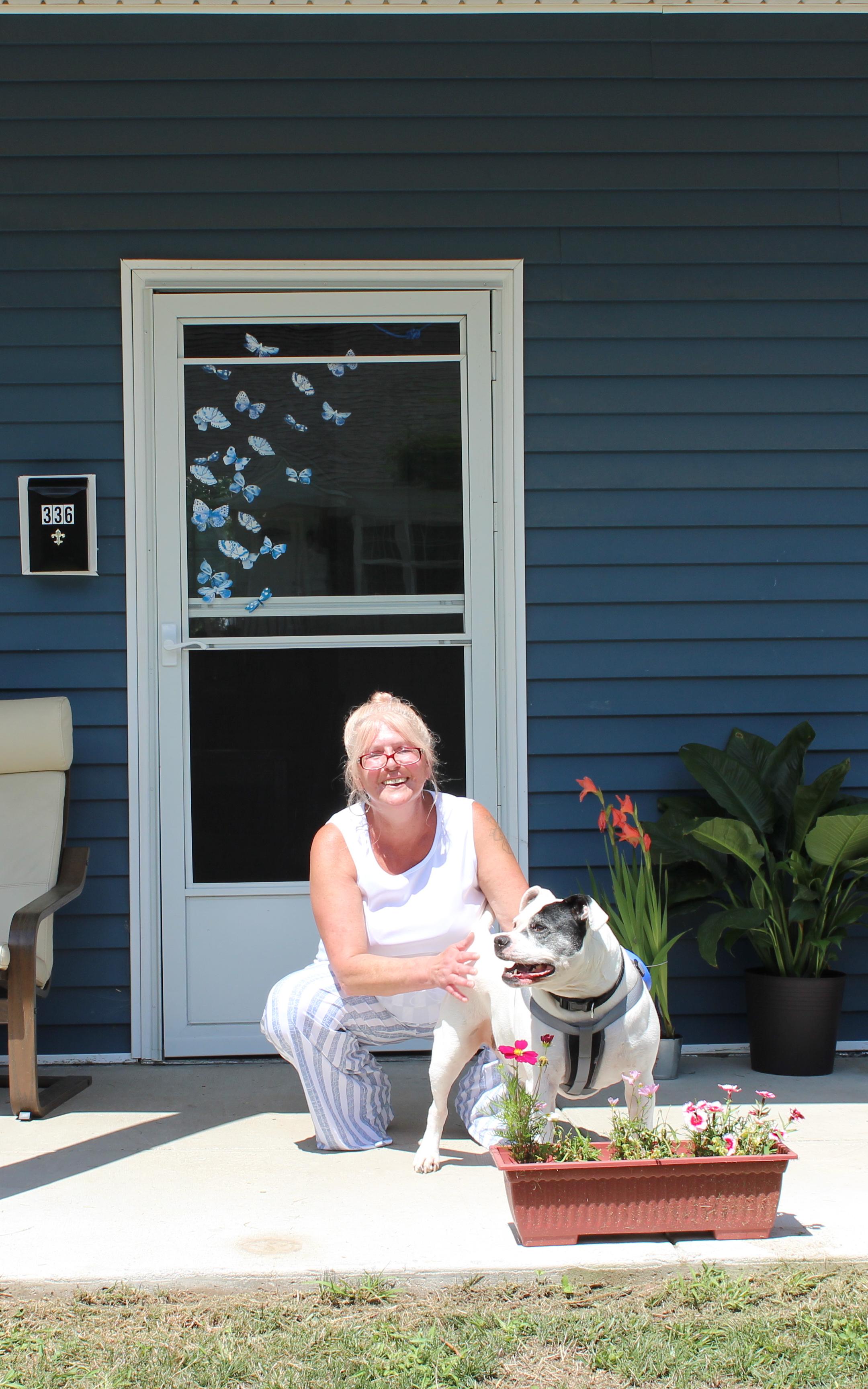 Beautiful News-Woman with dog in front of house.