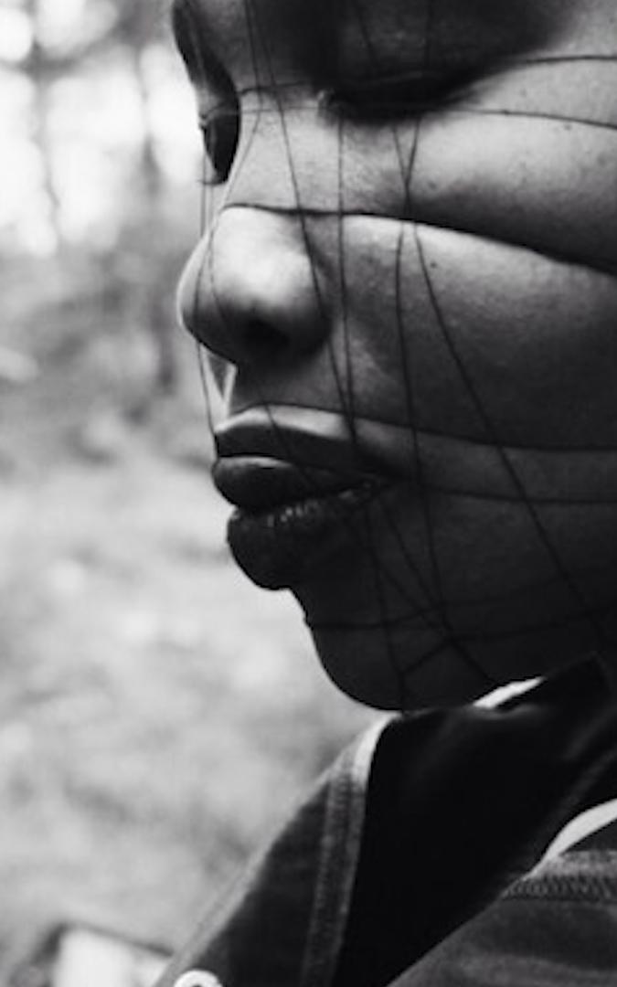 Black model with string on her face.
