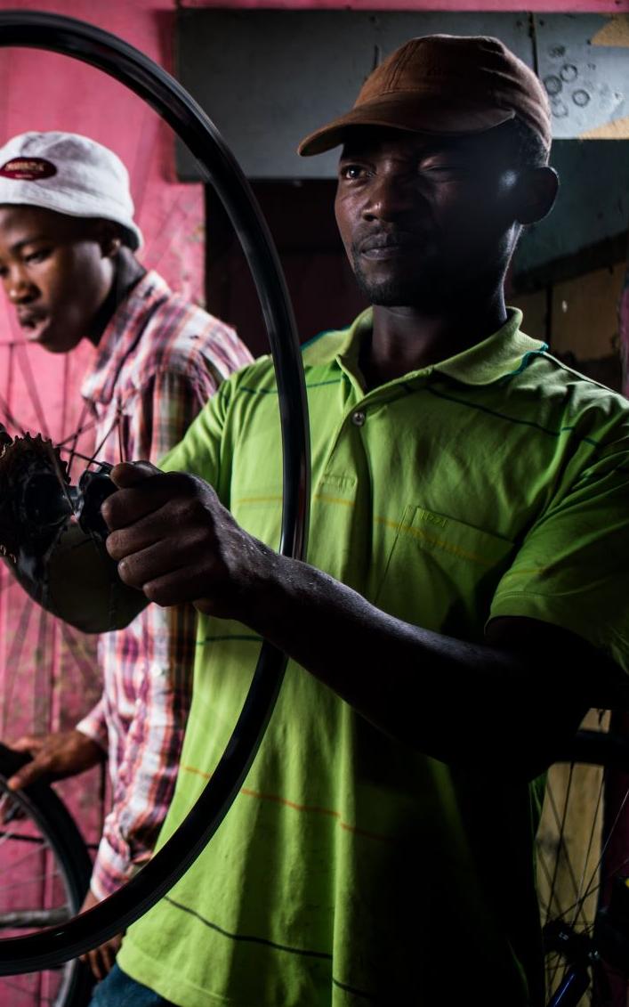 Black man inspecting bicycle wheel.