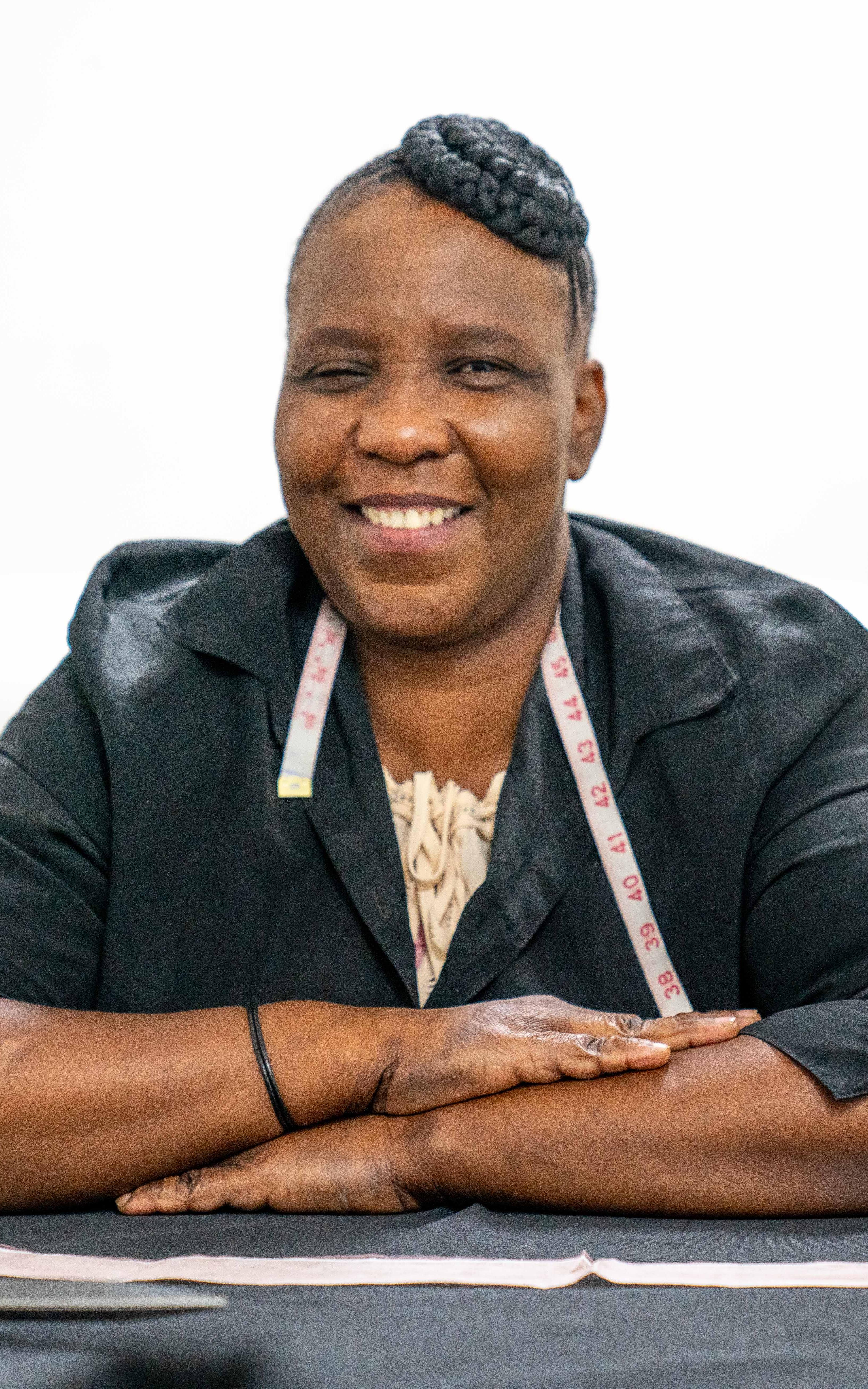 Beautiful News - Busisiwe Nxumalo sits proudly at her work station smiling with her measuring tape around her neck