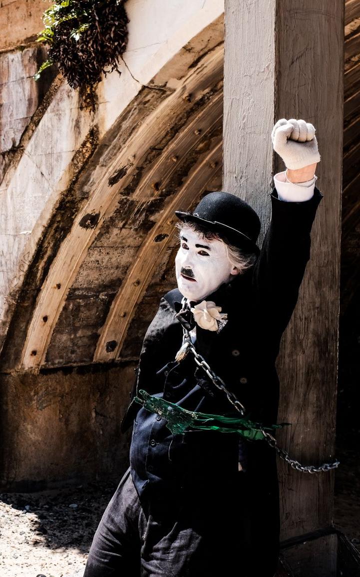 Mime with his fist in the air, tied to a pier support.