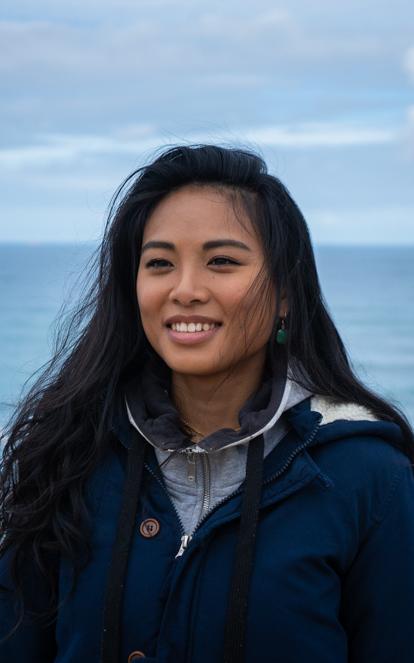 Asian woman smiles in front of the ocean