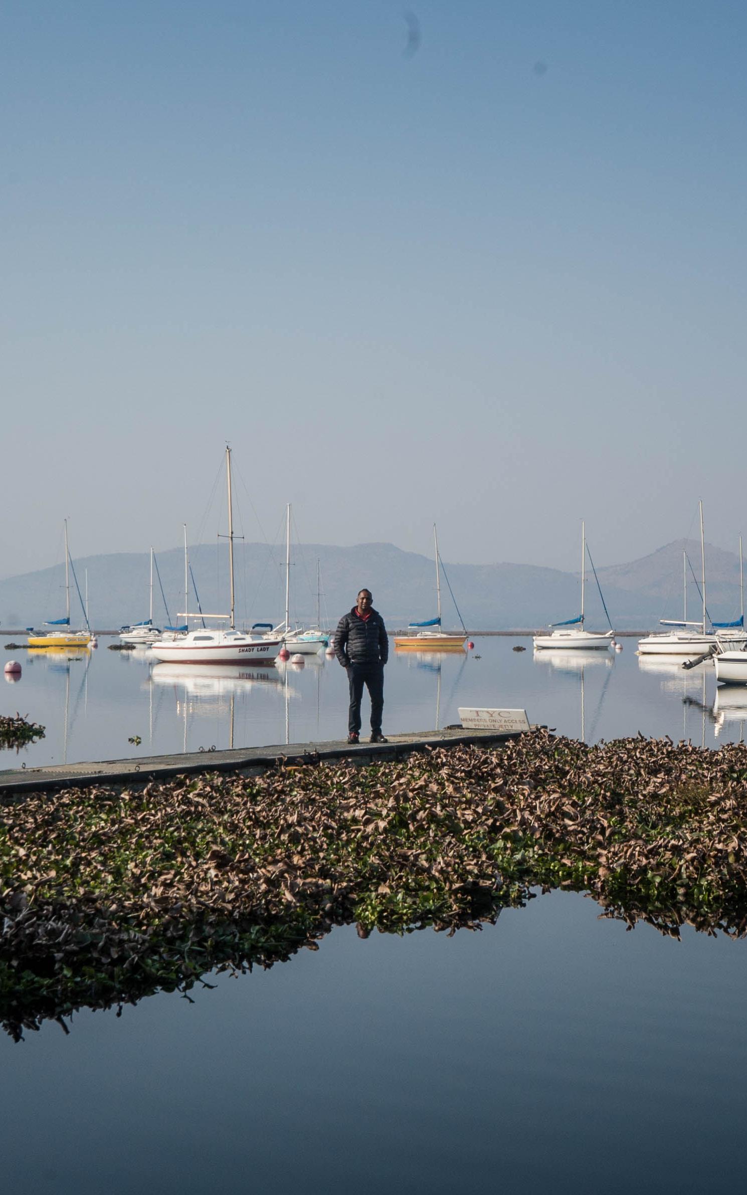 Man stands on a pier surrounded by boats