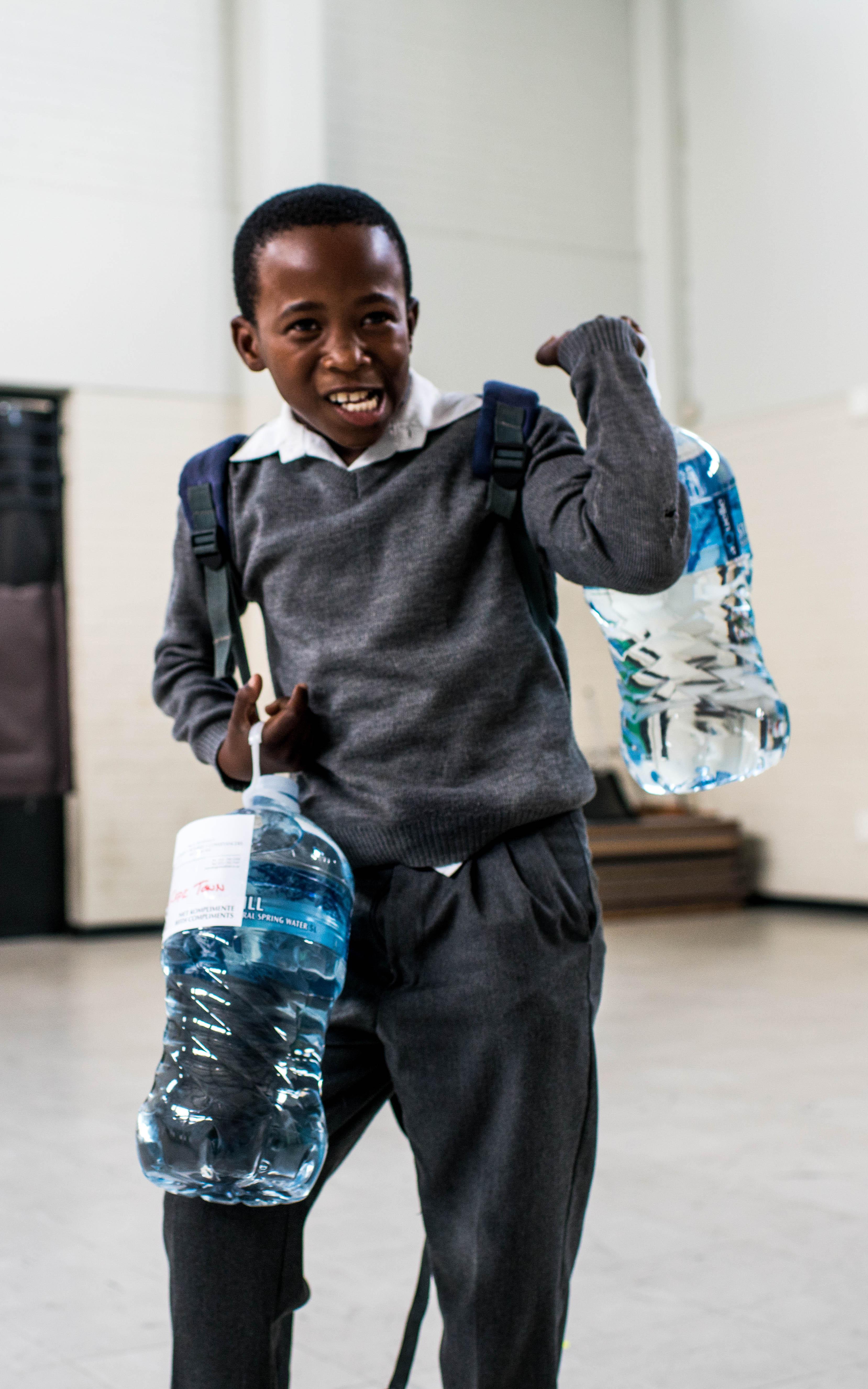 Black boy carrying 2 water bottles