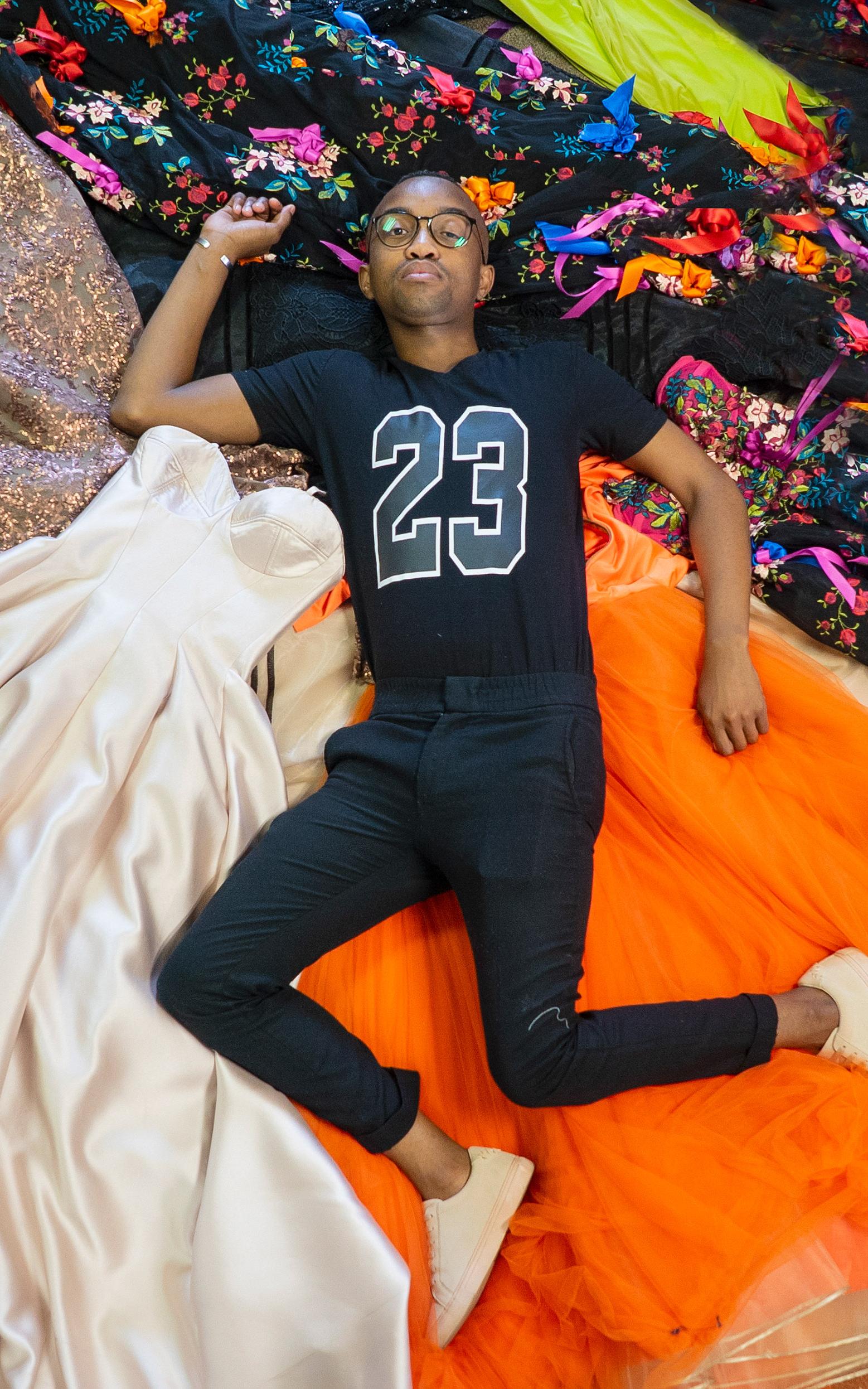 Man laying in between dresses