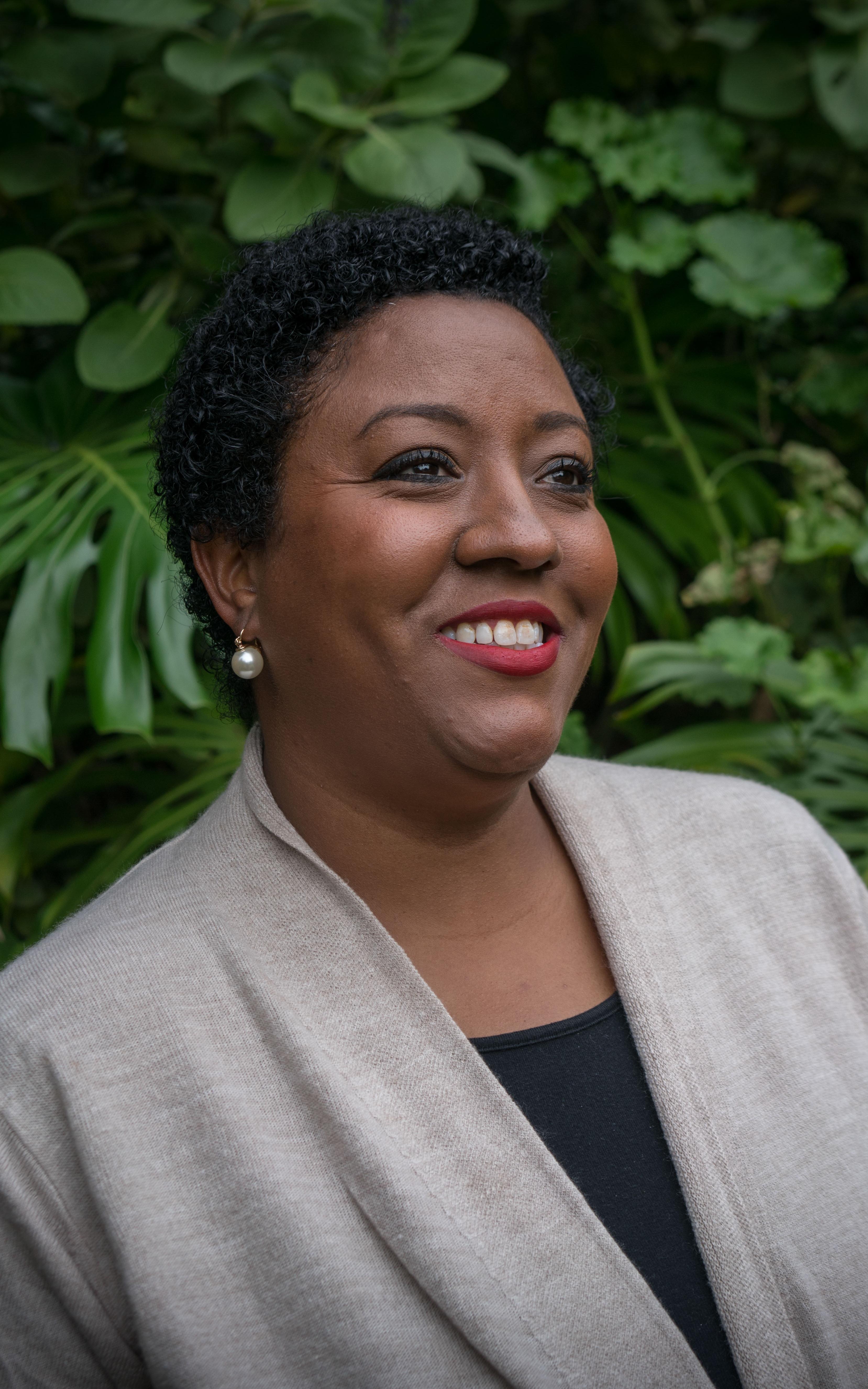 Woman smiling and looking off into the distance in front of trees