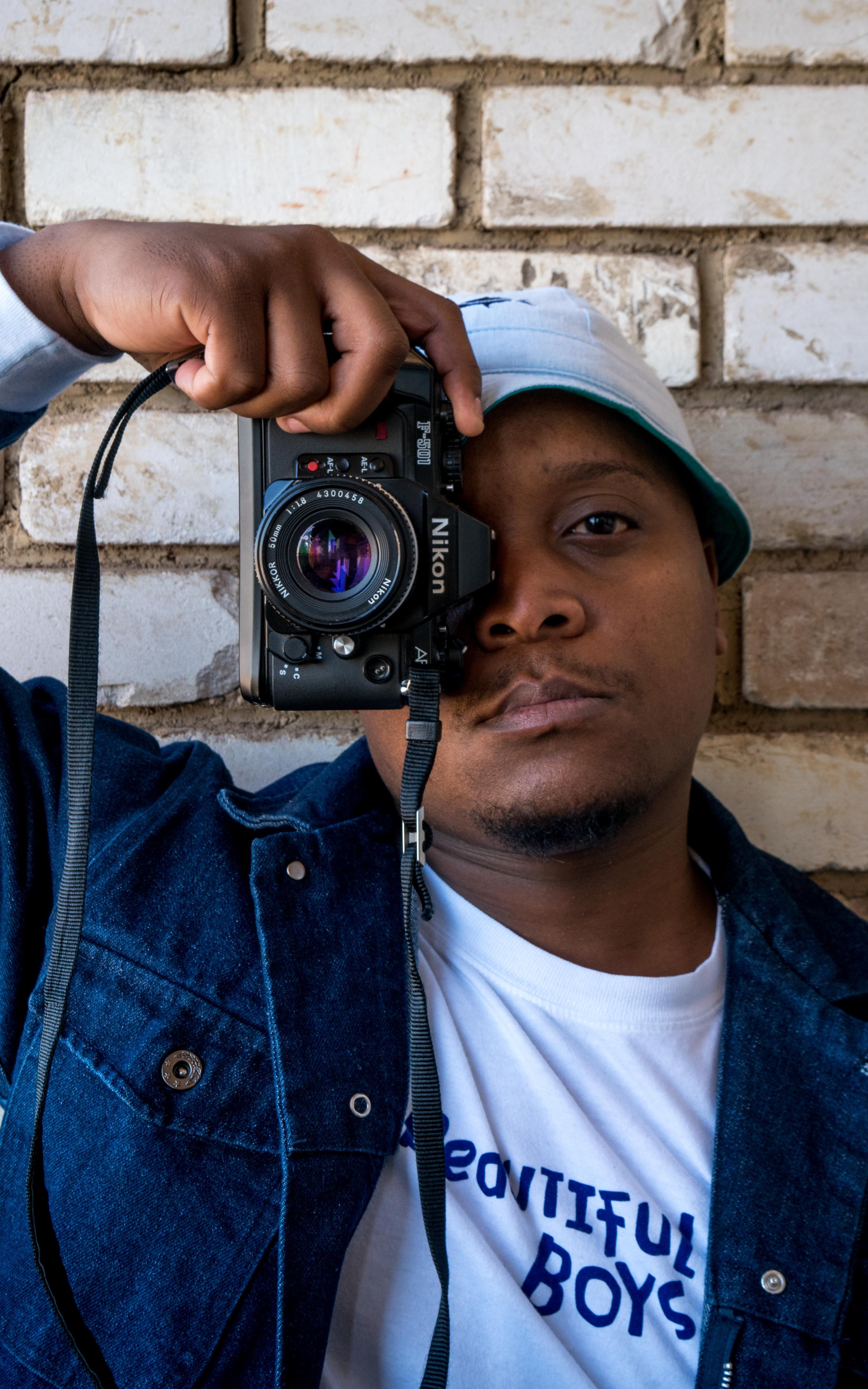 Man looks at the camera while covering one eye with a camera