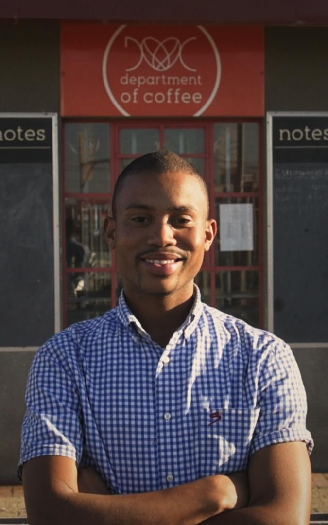 Black coffee business owner in front of his store.