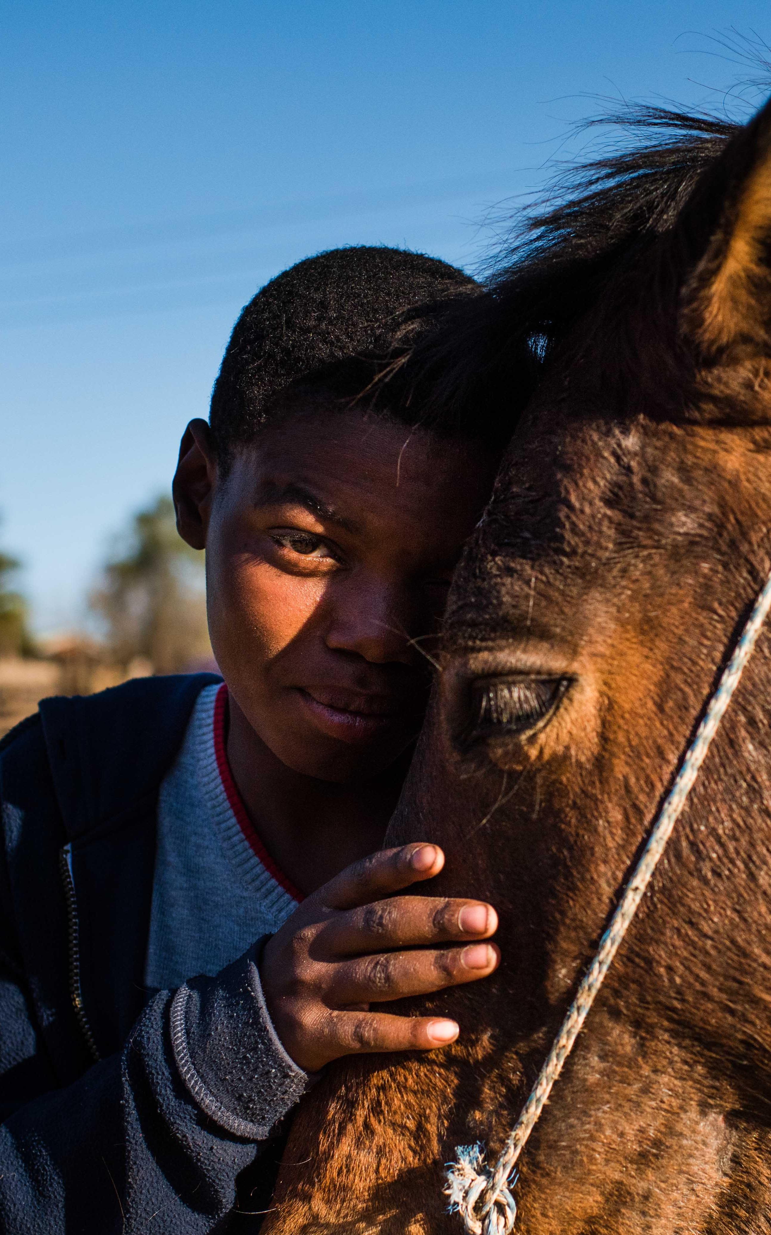 Black child smiling and embracing horse