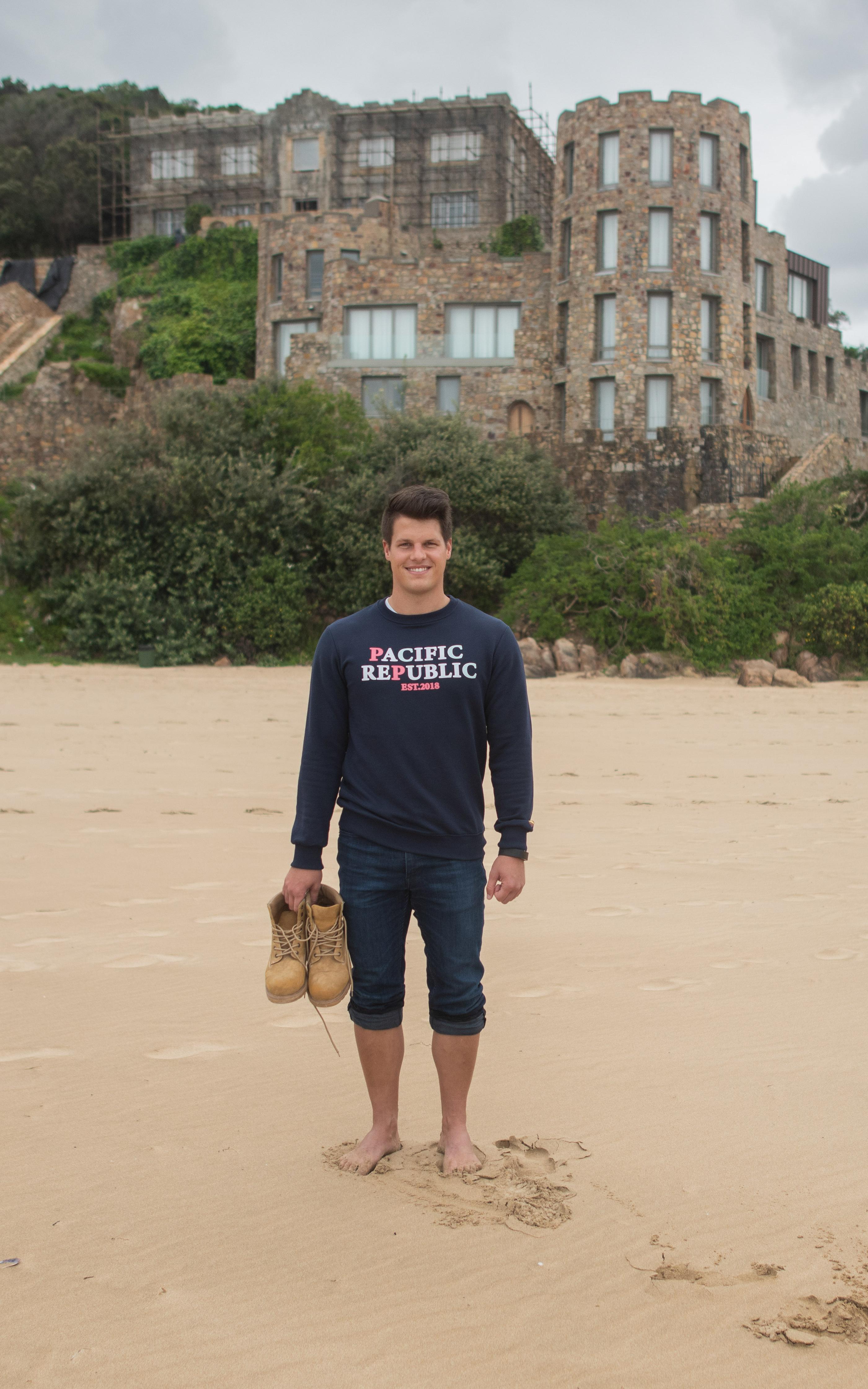 Man stands on a beach in front of a castle