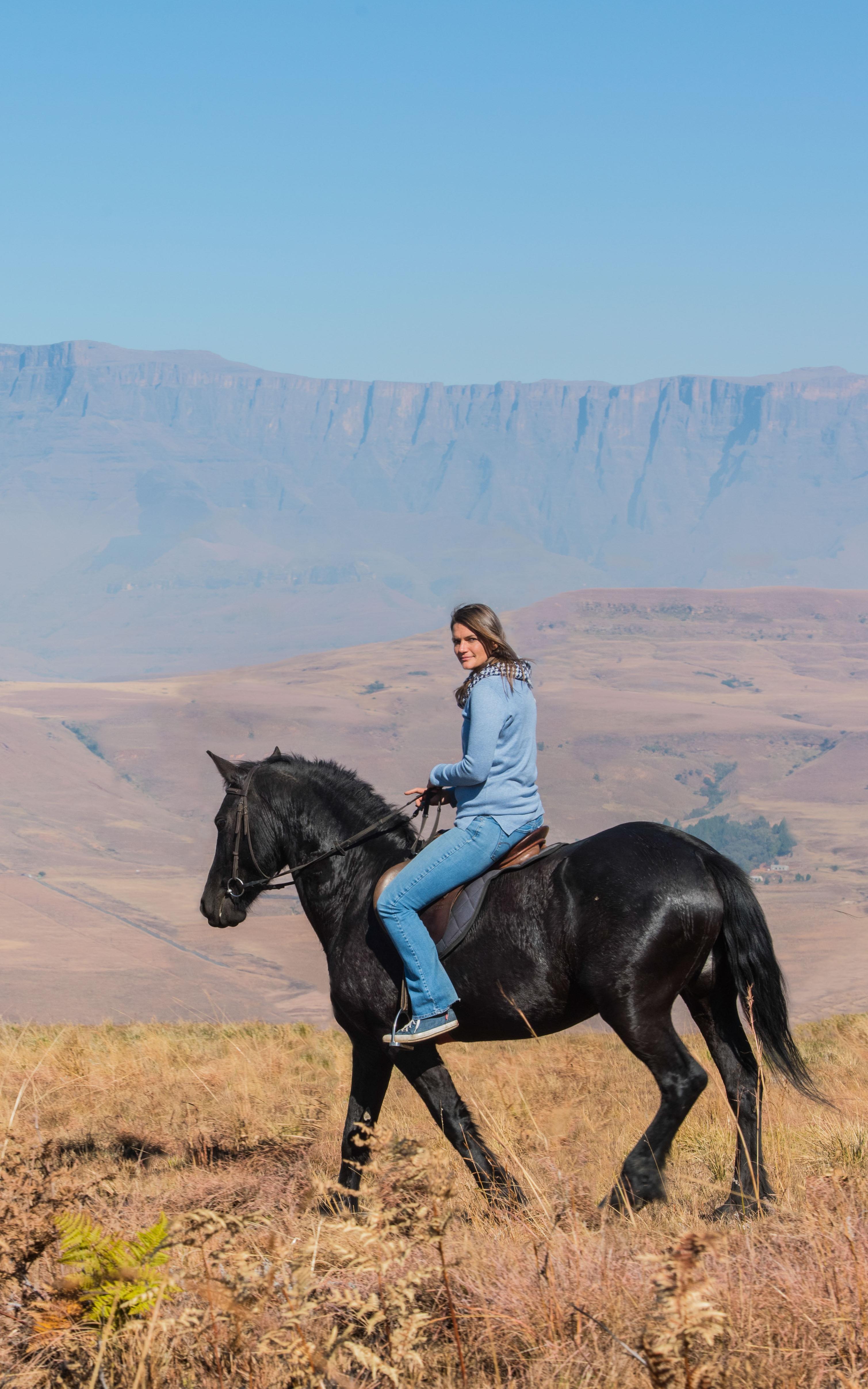 Woman rides a horse with mountains in the background