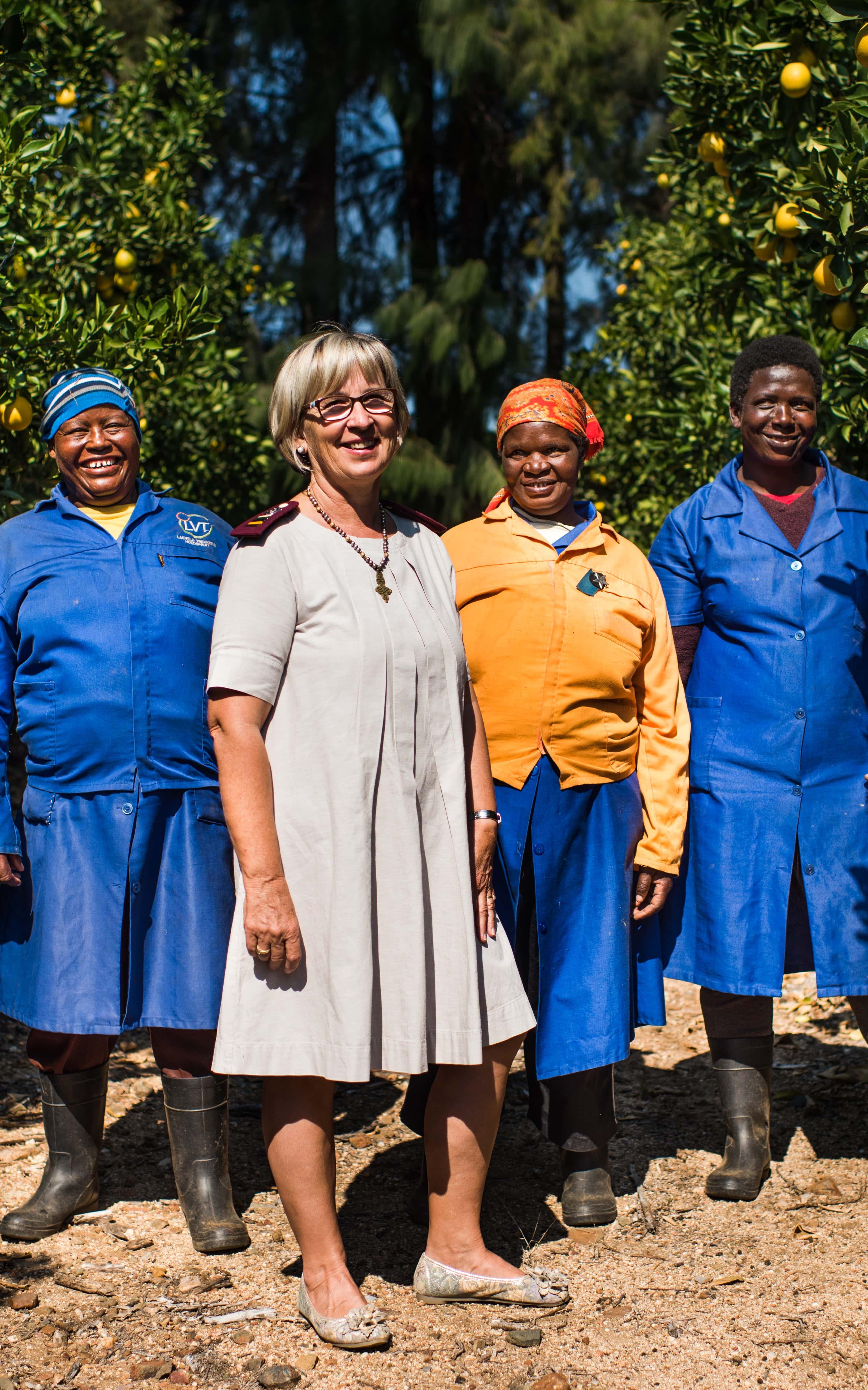 Four women stand surrounded by lemon trees