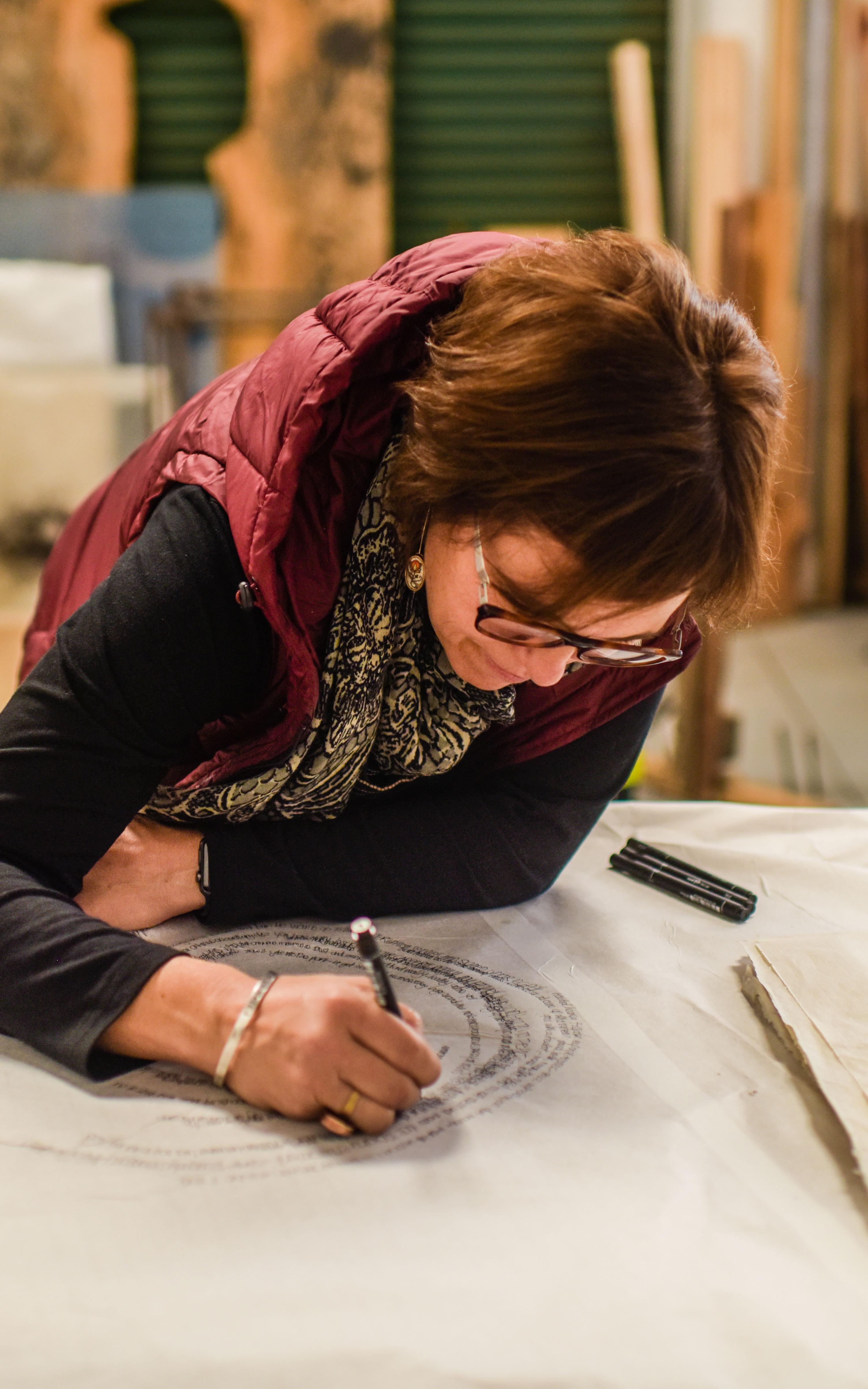 Woman leans on a table and sketches 