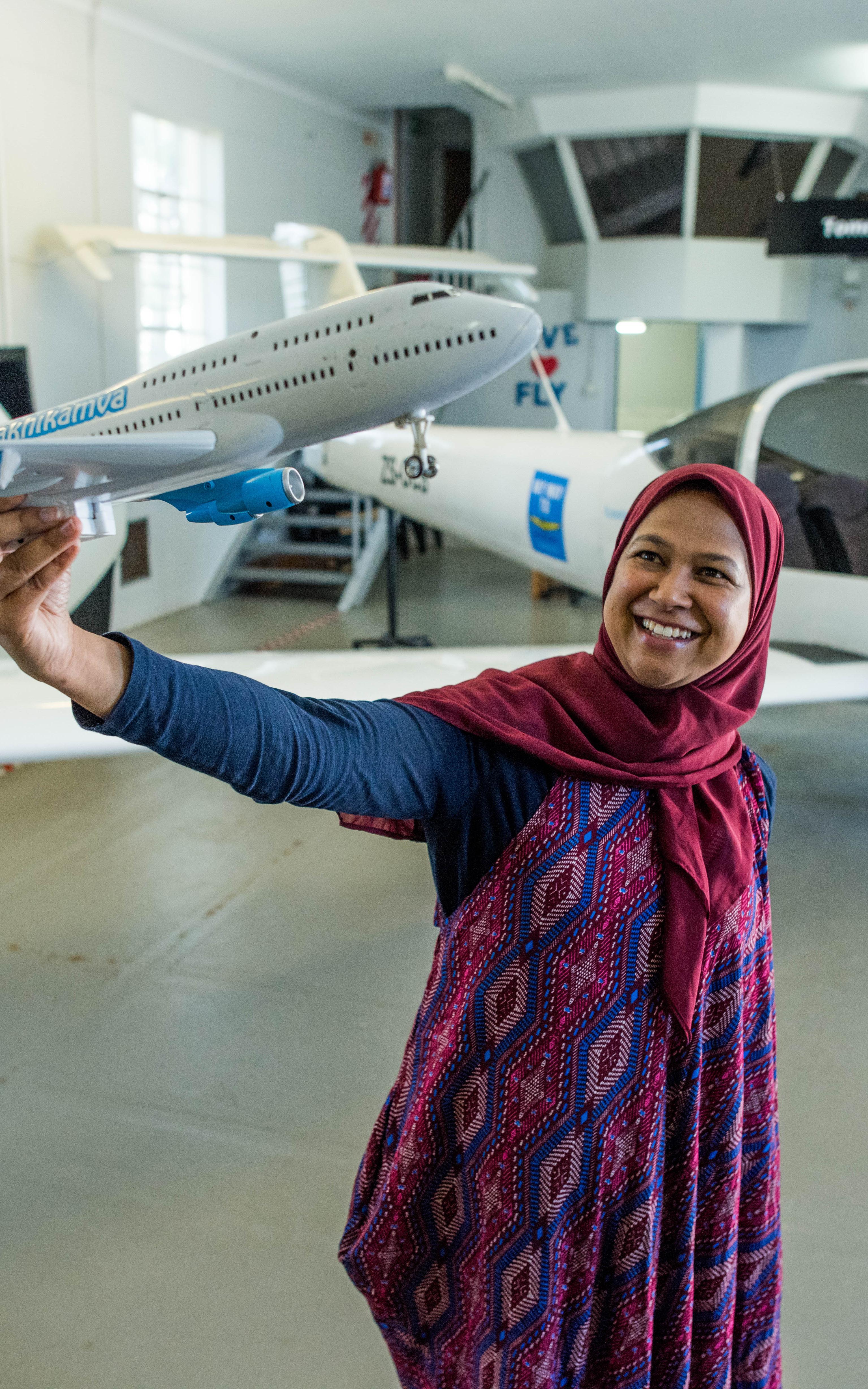 Muslim flight instructor holding model airplane.