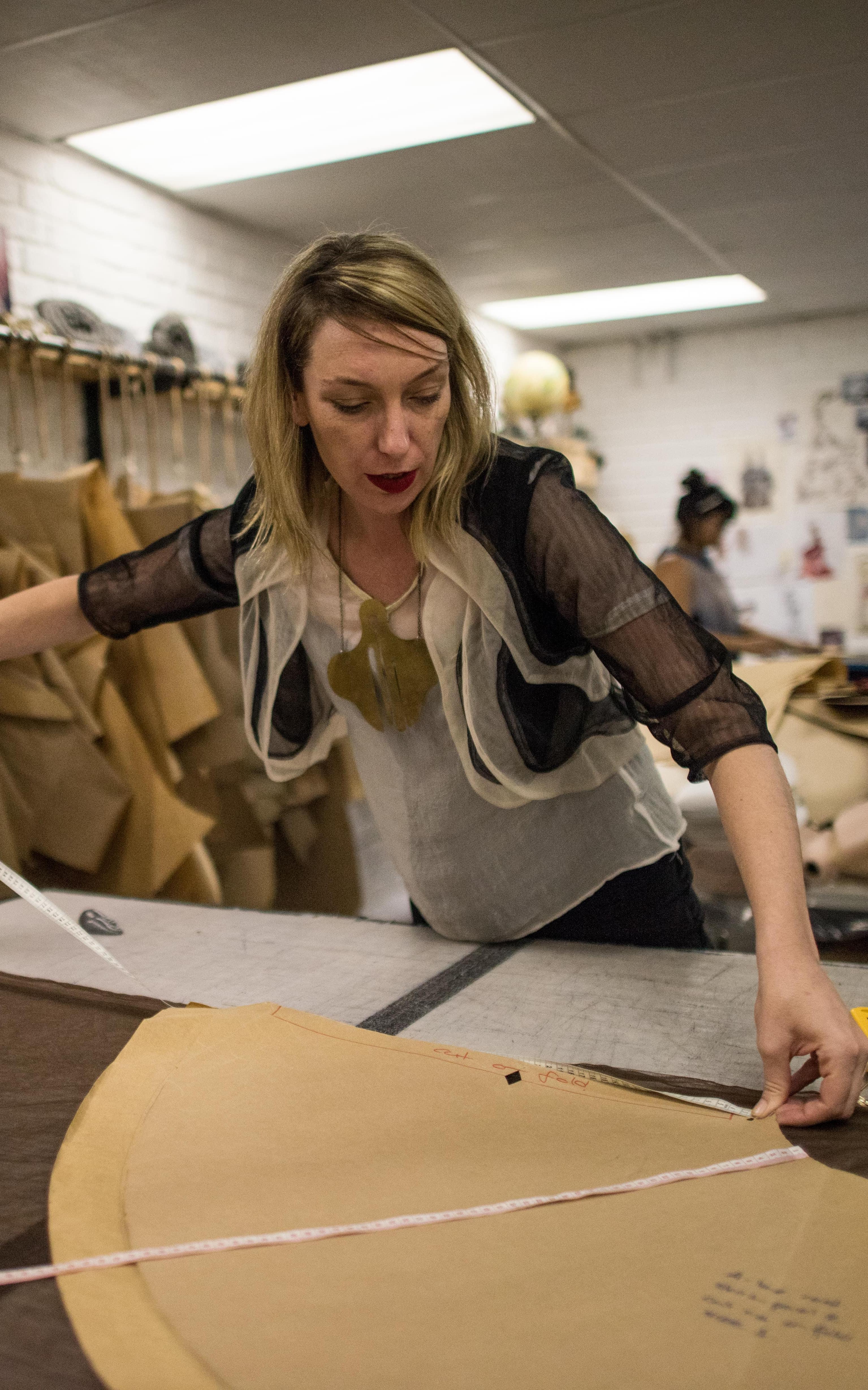 White woman measuring fabric with a tape measure