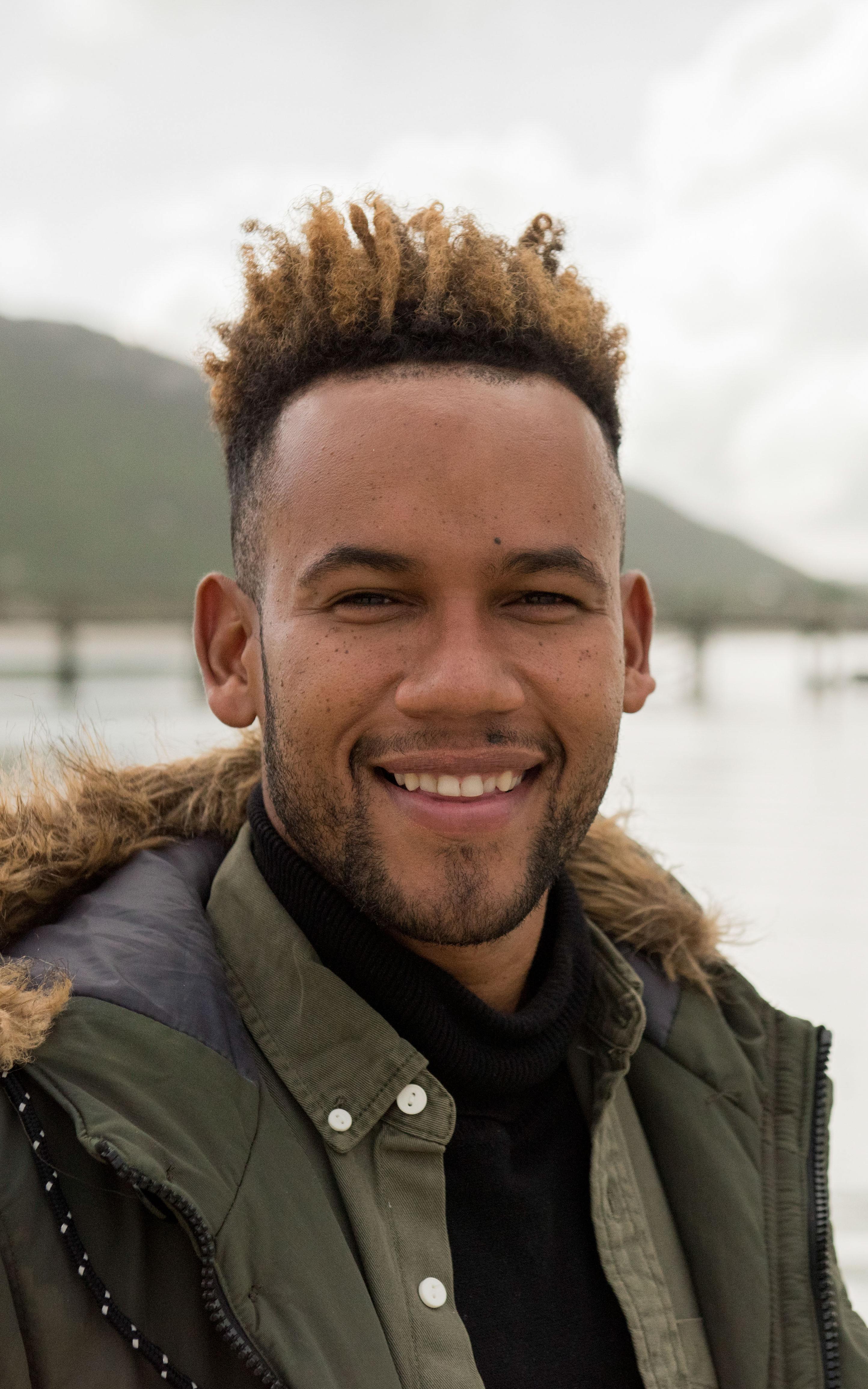 Man smiles at the camera standing in front of a lagoon
