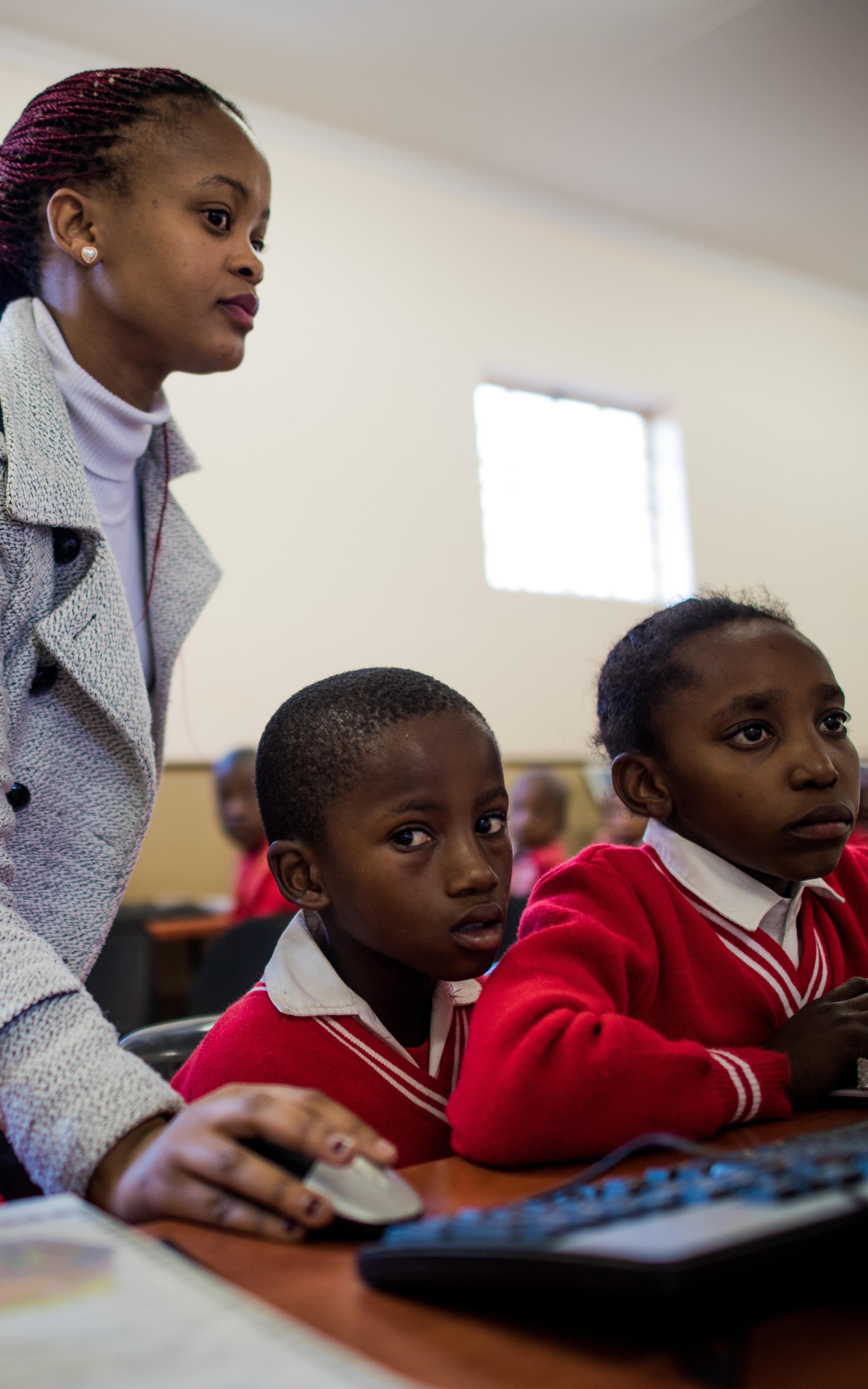 Teacher showing students how to use a computer