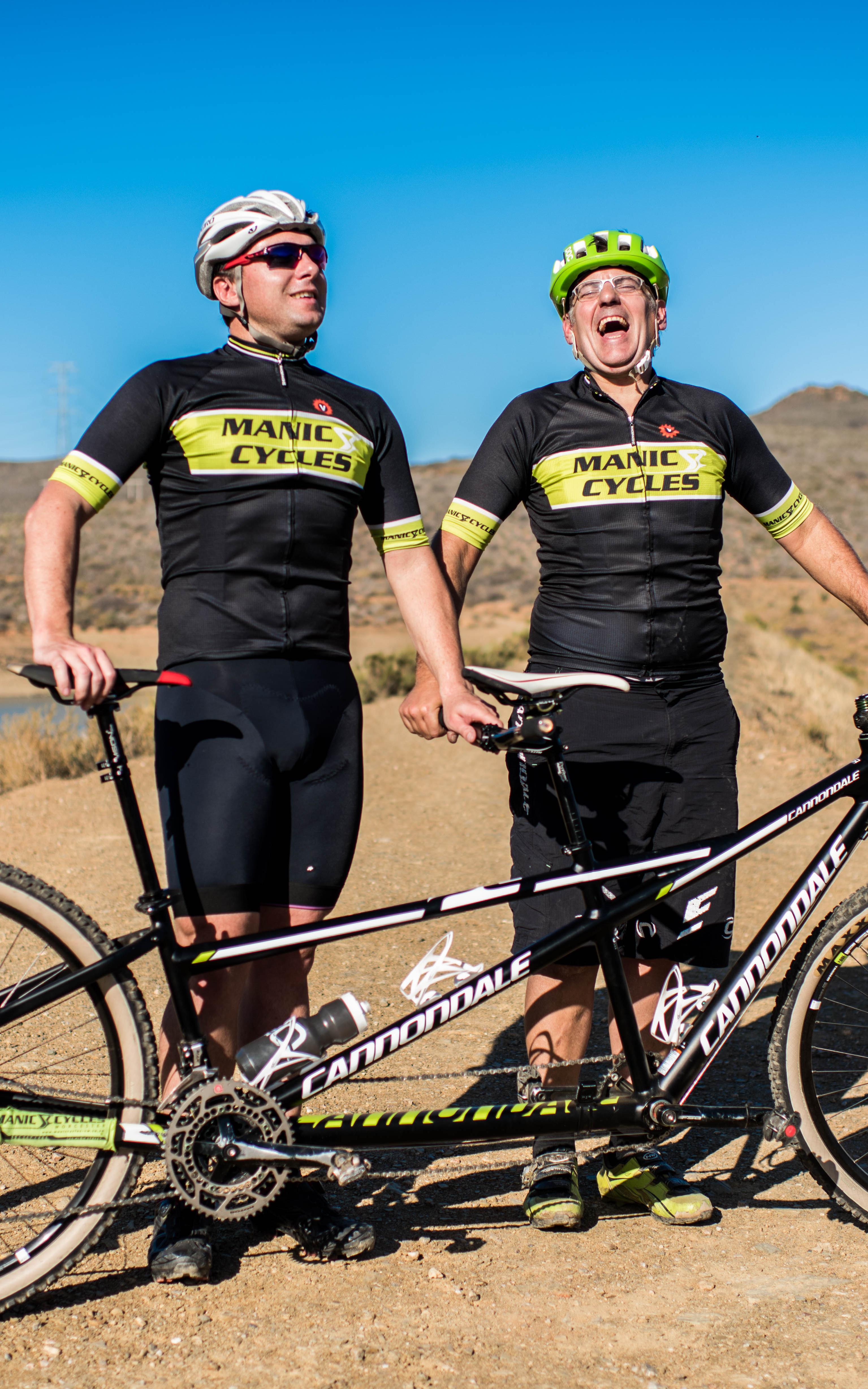 Two men standing by tandem bicycle