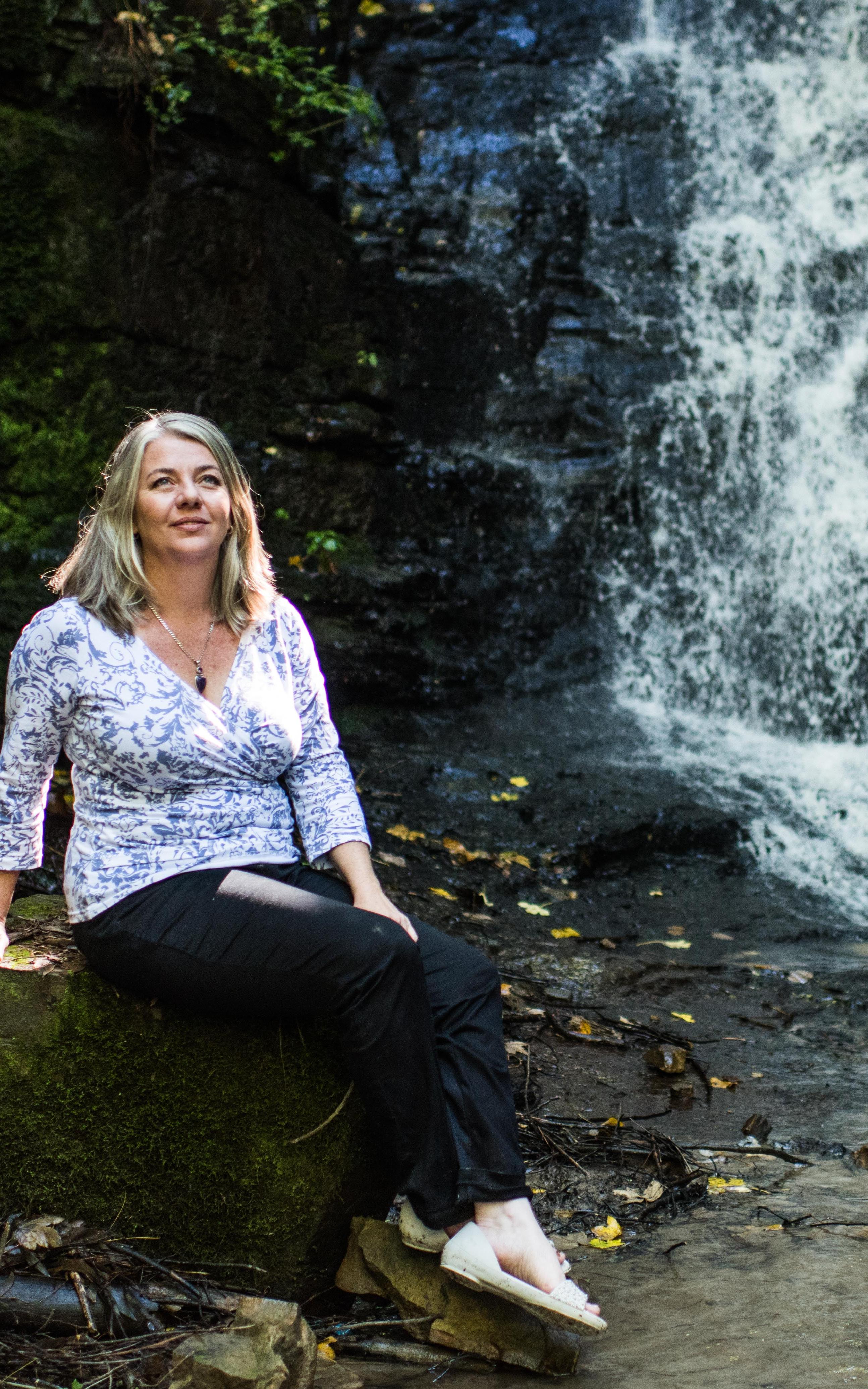 Woman sits next to a waterfall