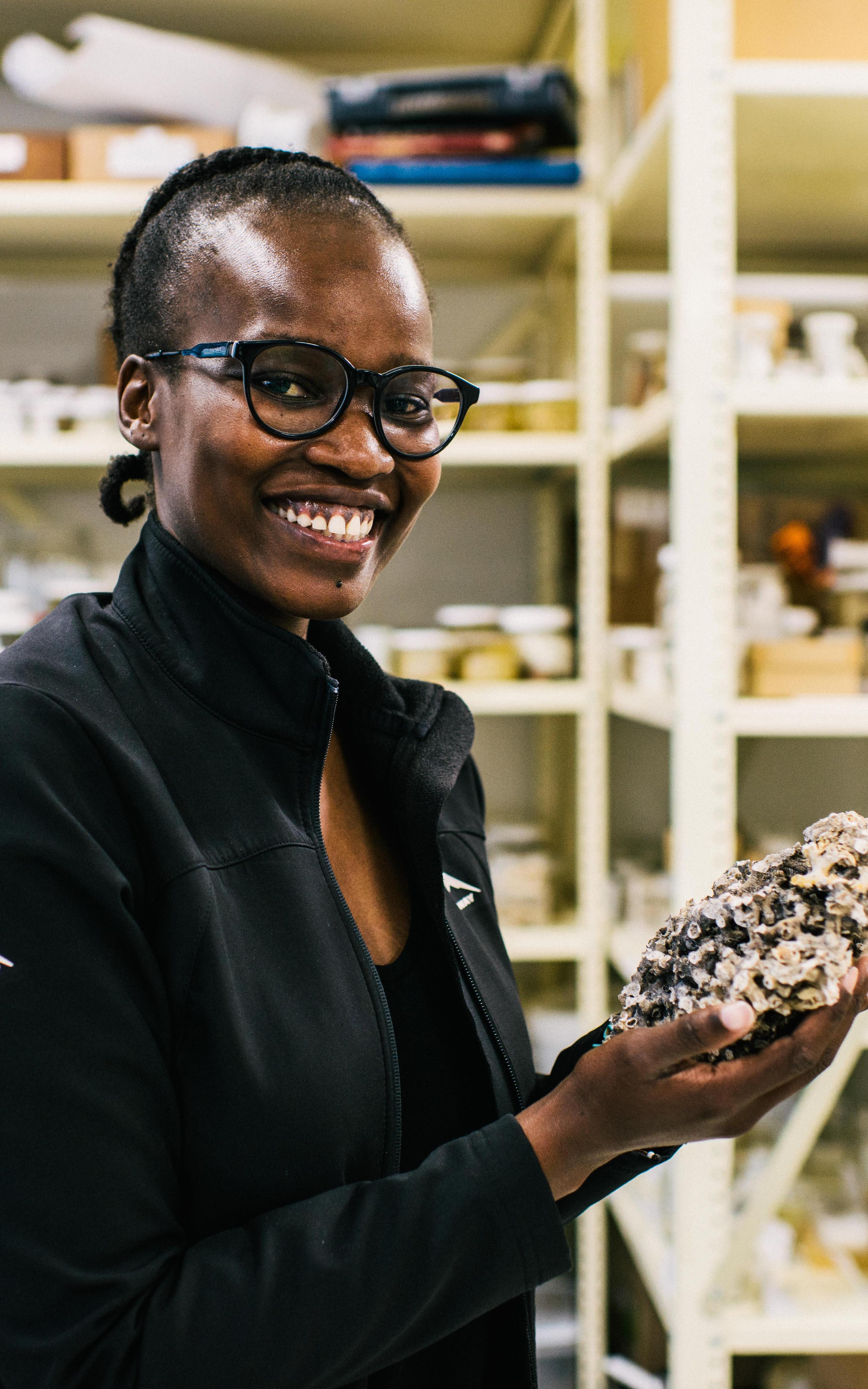 Woman holding shell, smiling at camera