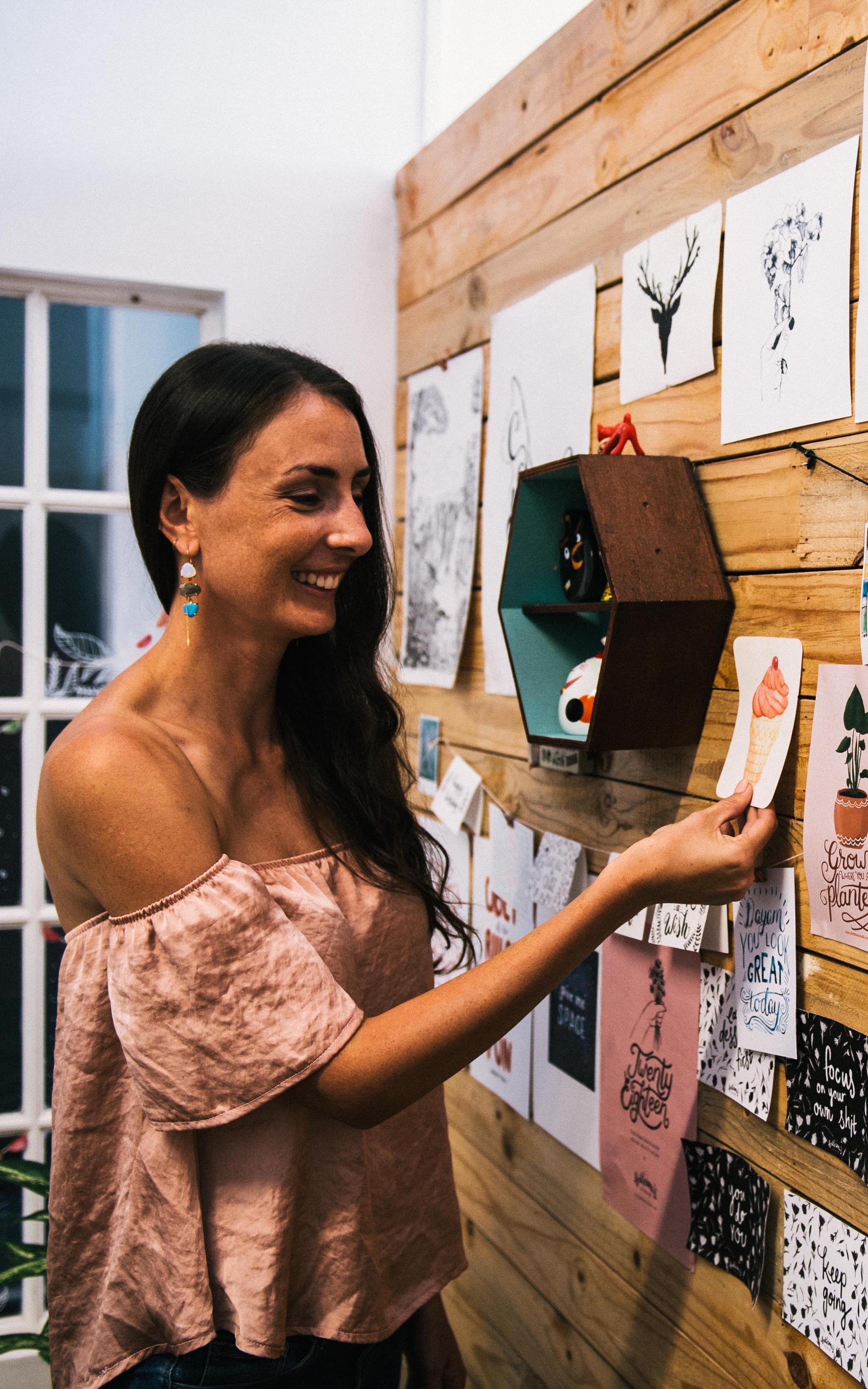 Woman smiles while looking at a wall of artwork