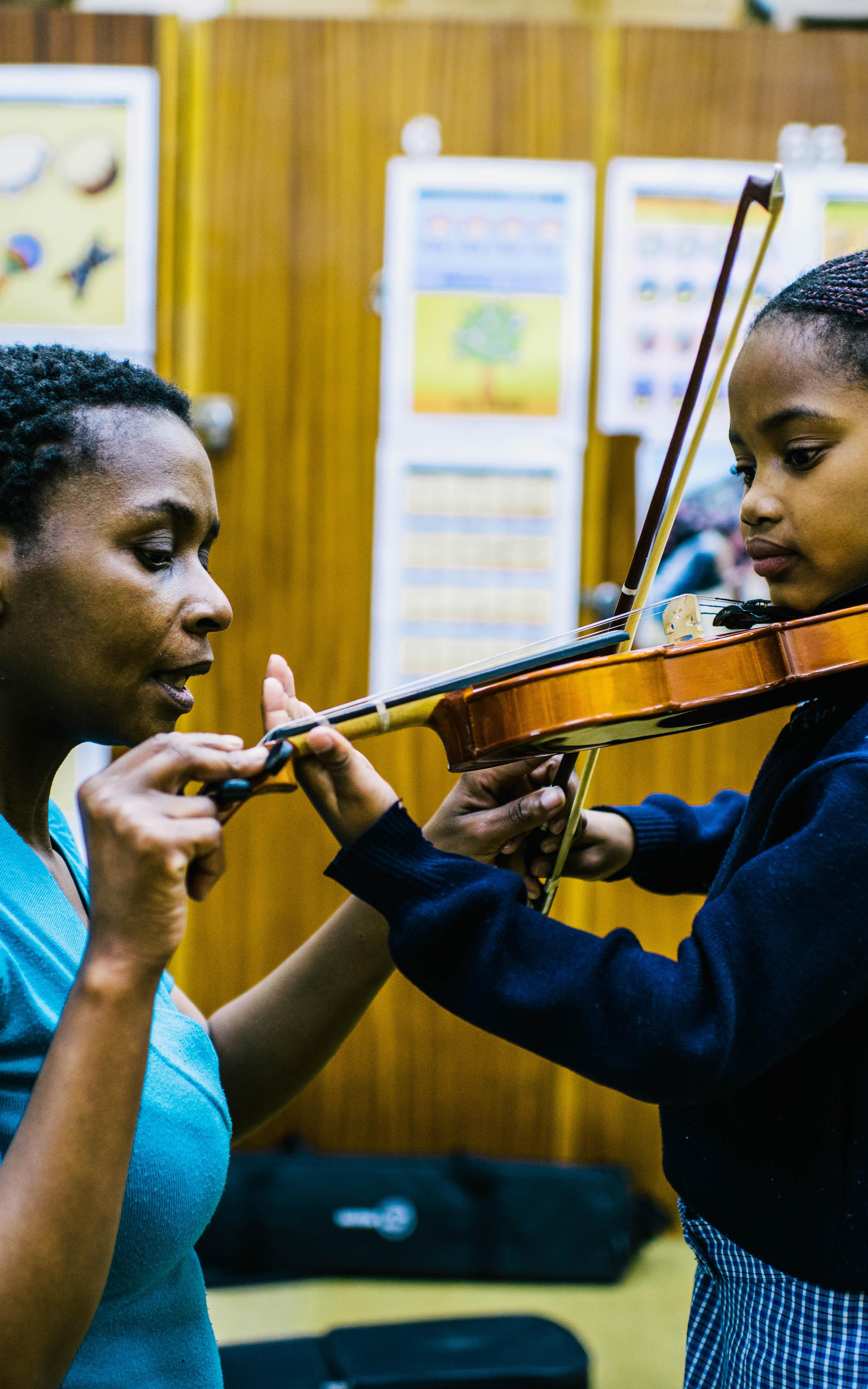 Woman showing girl how to play violin