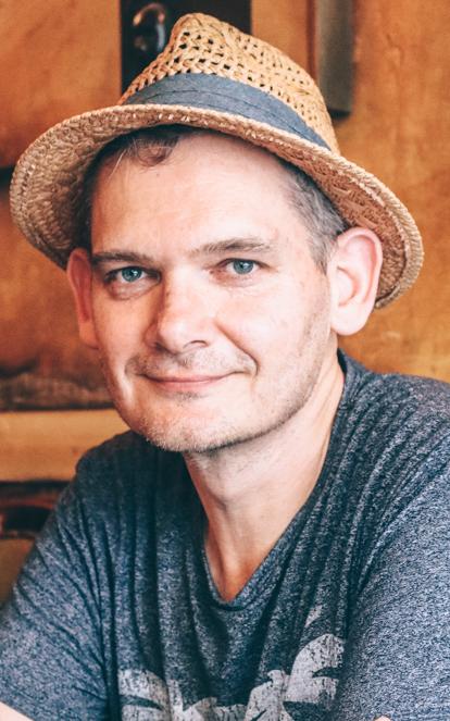 Man wearing a hat smiles at the camera