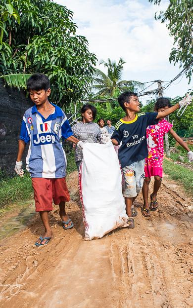 Beautiful News - Children in Cambodia walking along a sand road collecting litter