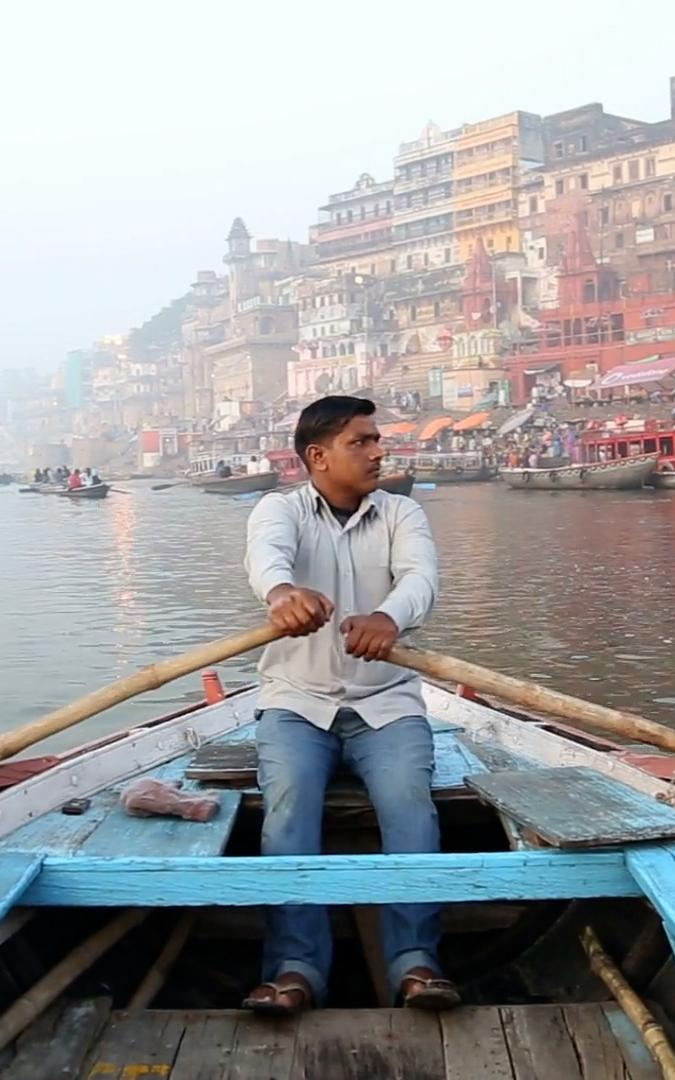 Beautiful News - Varanasi India, man peacefully rowing with city in background
