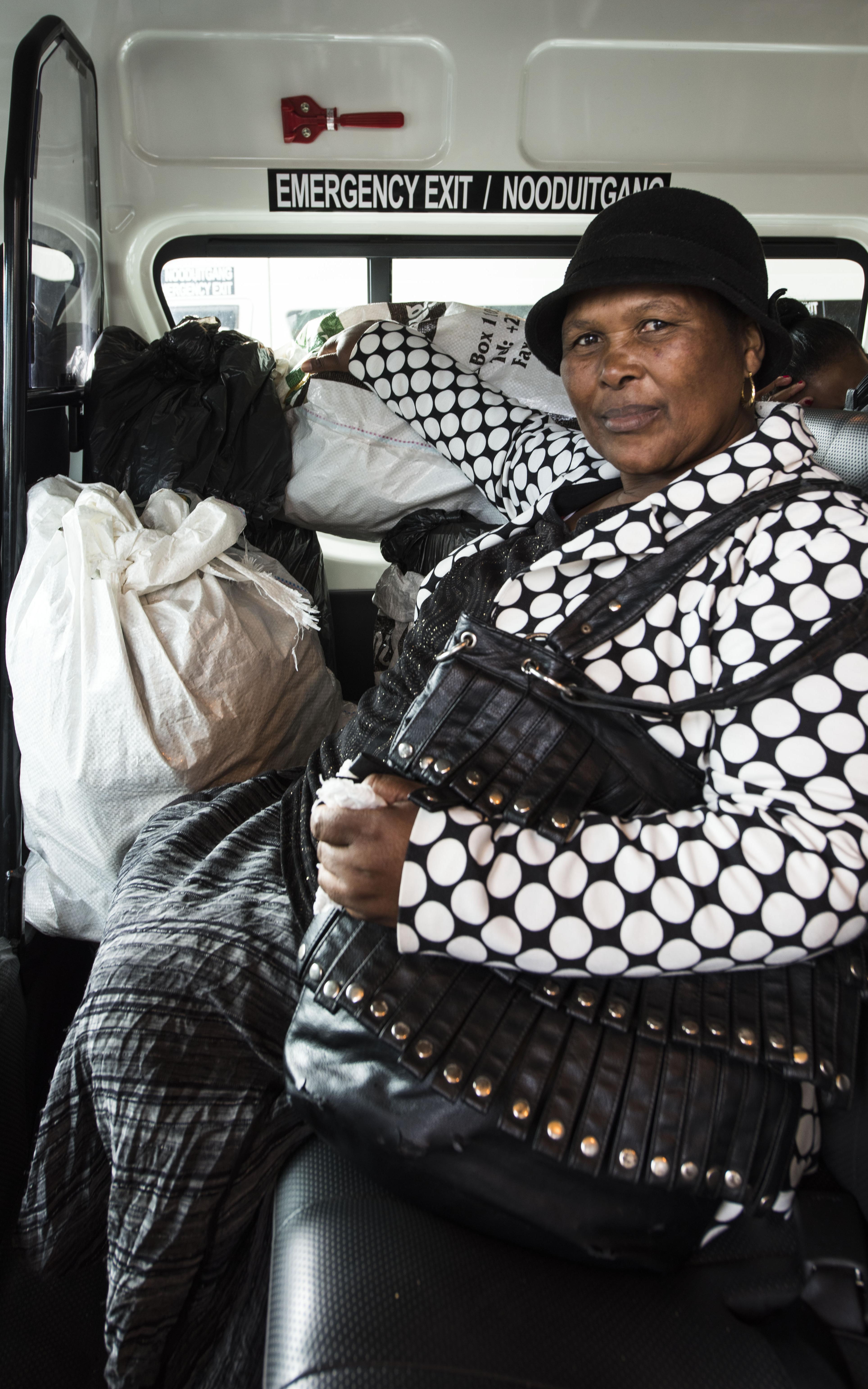Black woman in taxi sitting next to bagged food for community.