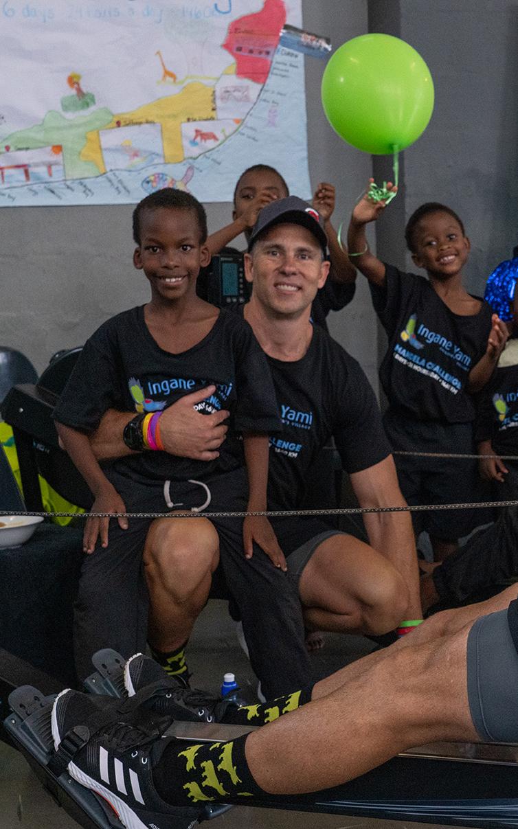 Man stationary rowing with kids in background.
