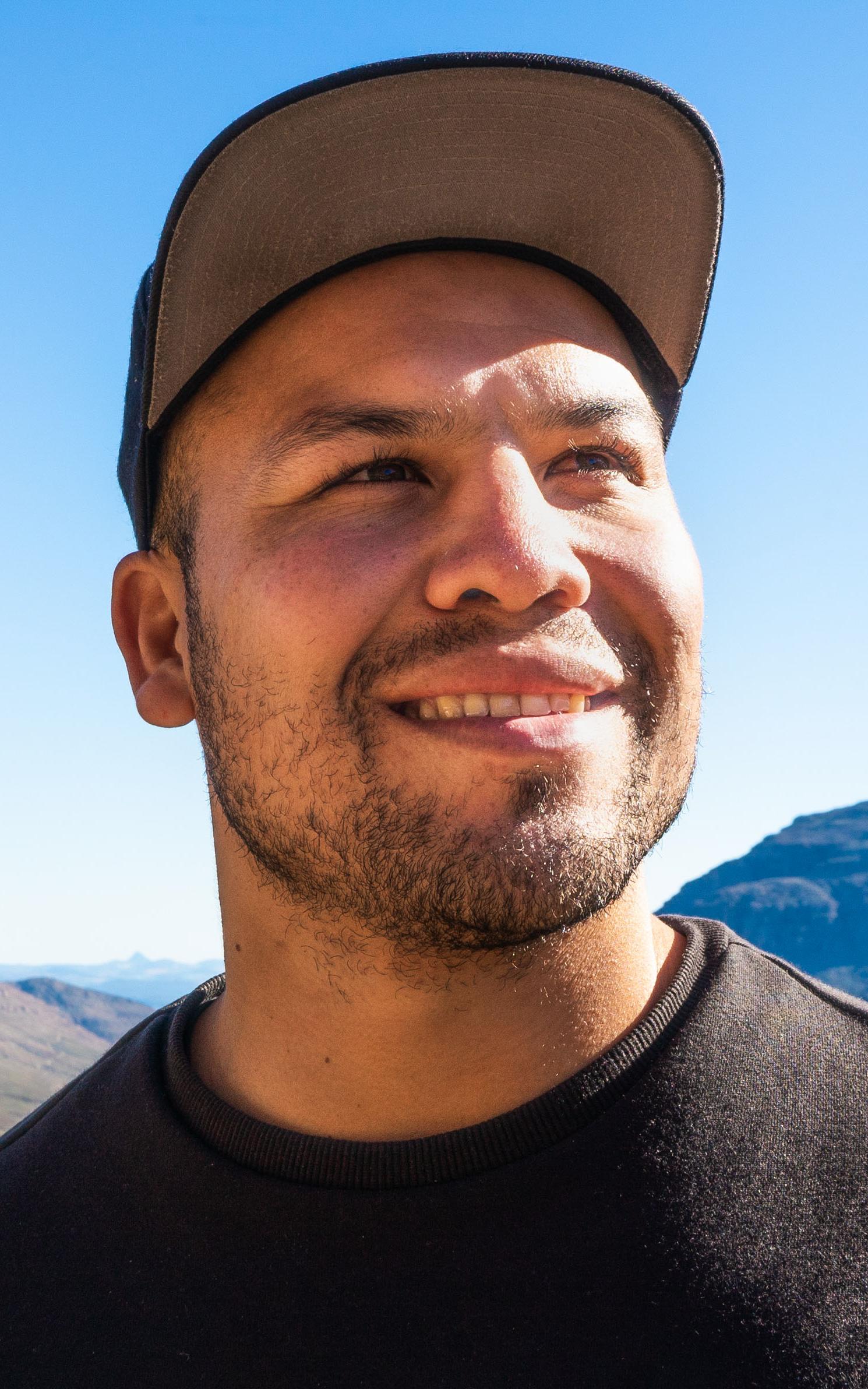 Man smiles and looks off into the distance with mountains in the background
