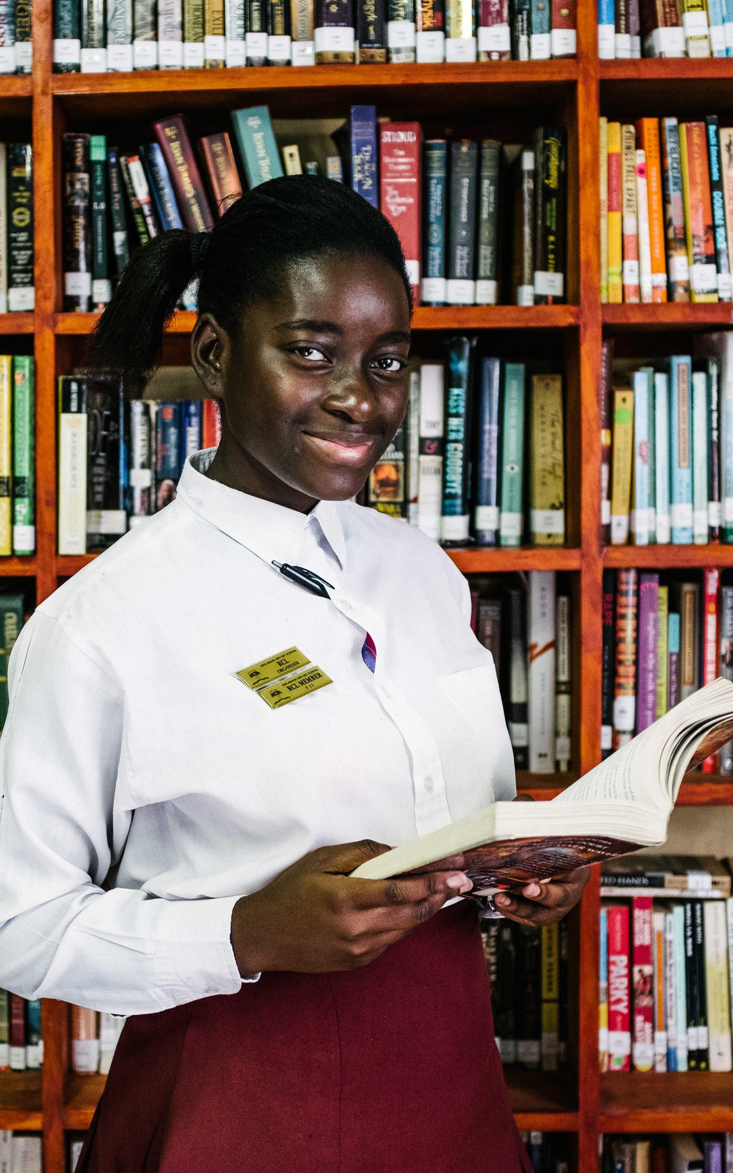 Black girl smiling in front of books