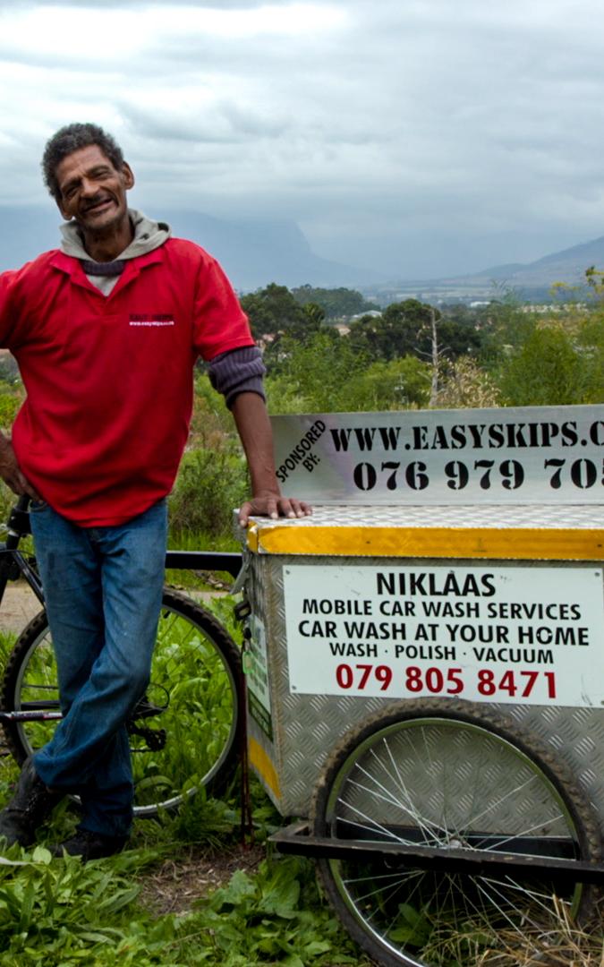 Man standing next to mobile car wash