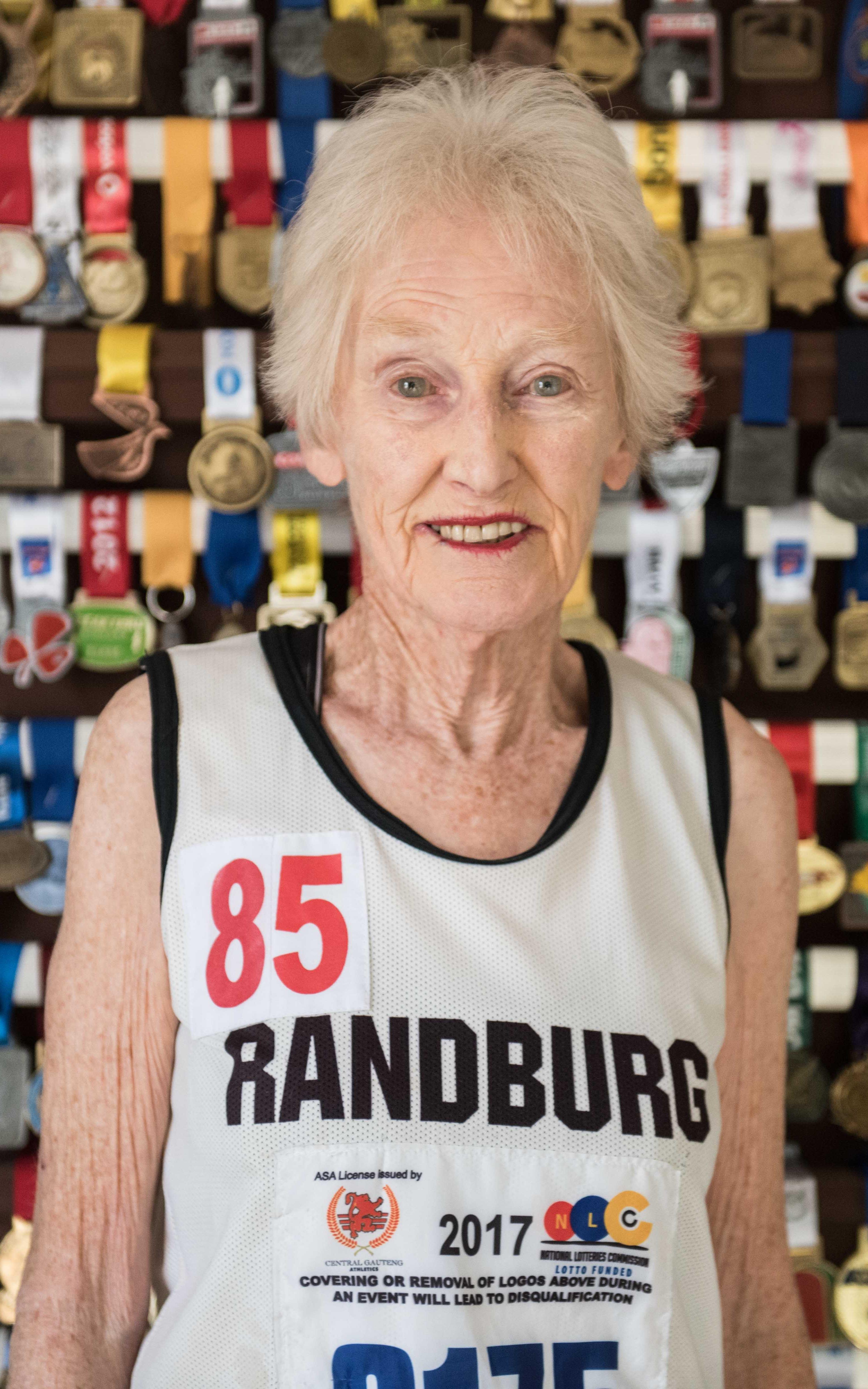 Old woman smiling in front of medals
