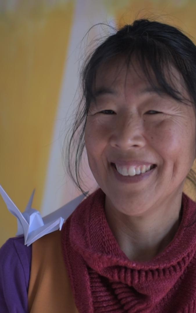 Asian woman with origami art on her shoulder.
