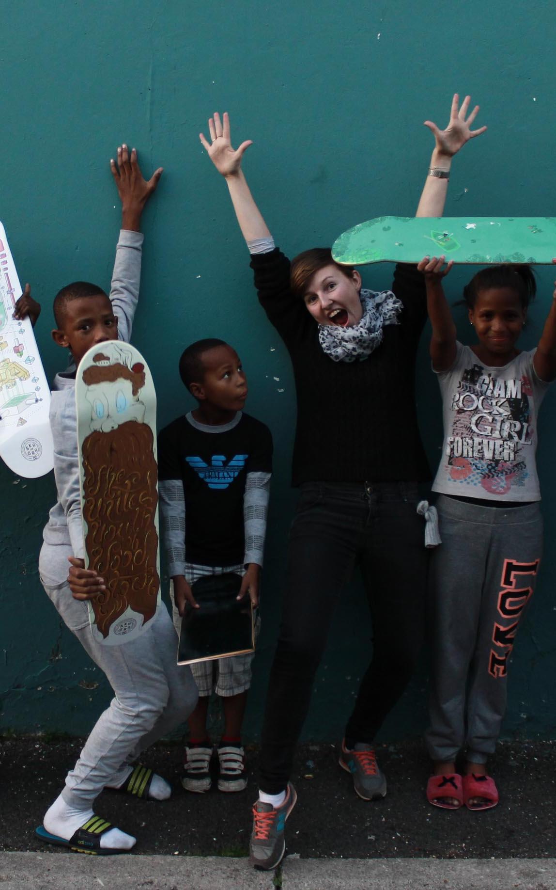 Woman with group of kids holding skareboards.