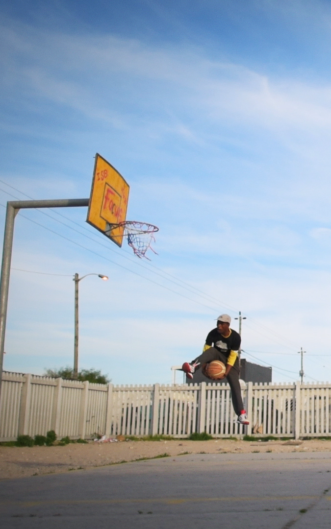 Black basketball coach jumping towards the net.