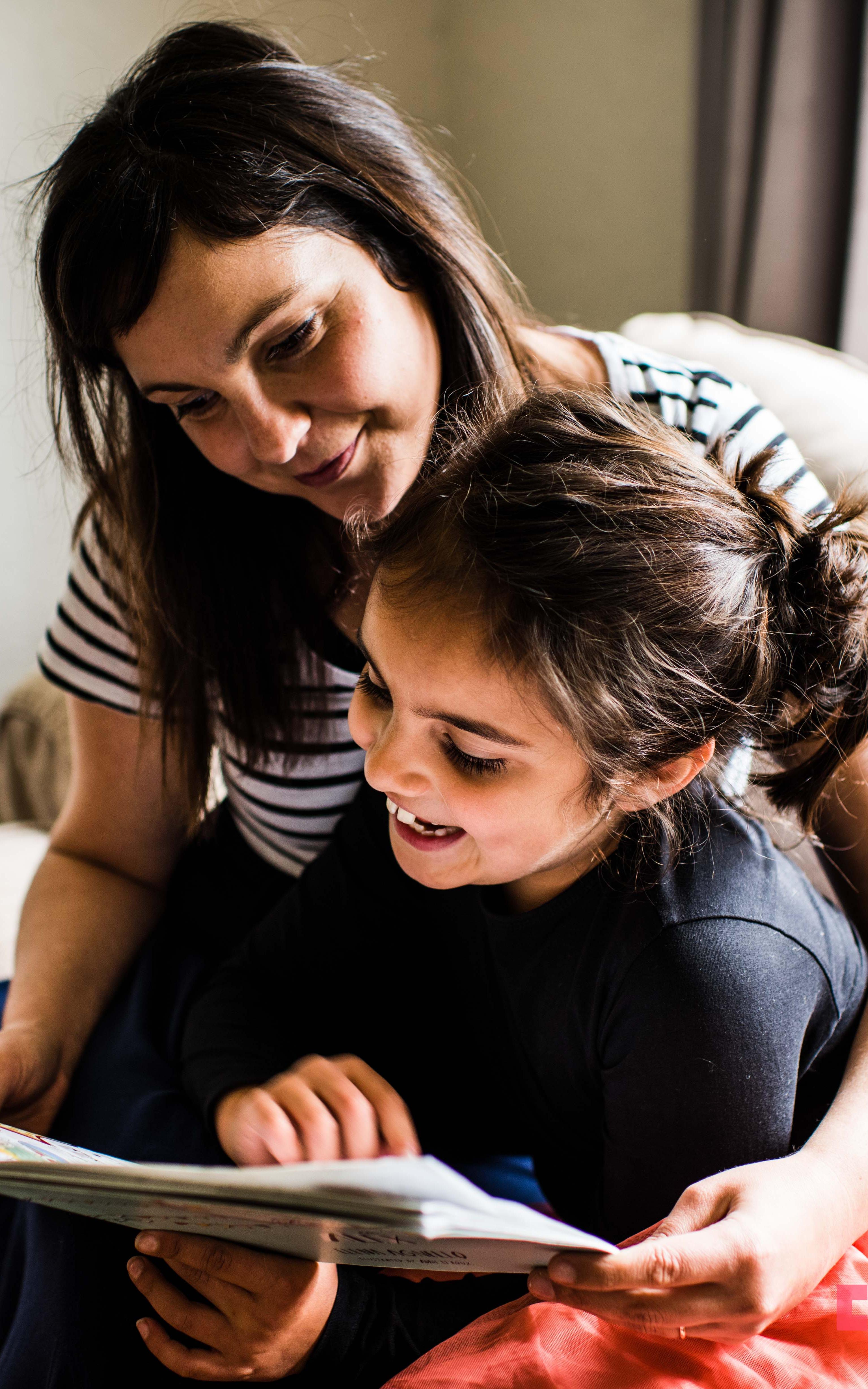 Mother reading book with daughter