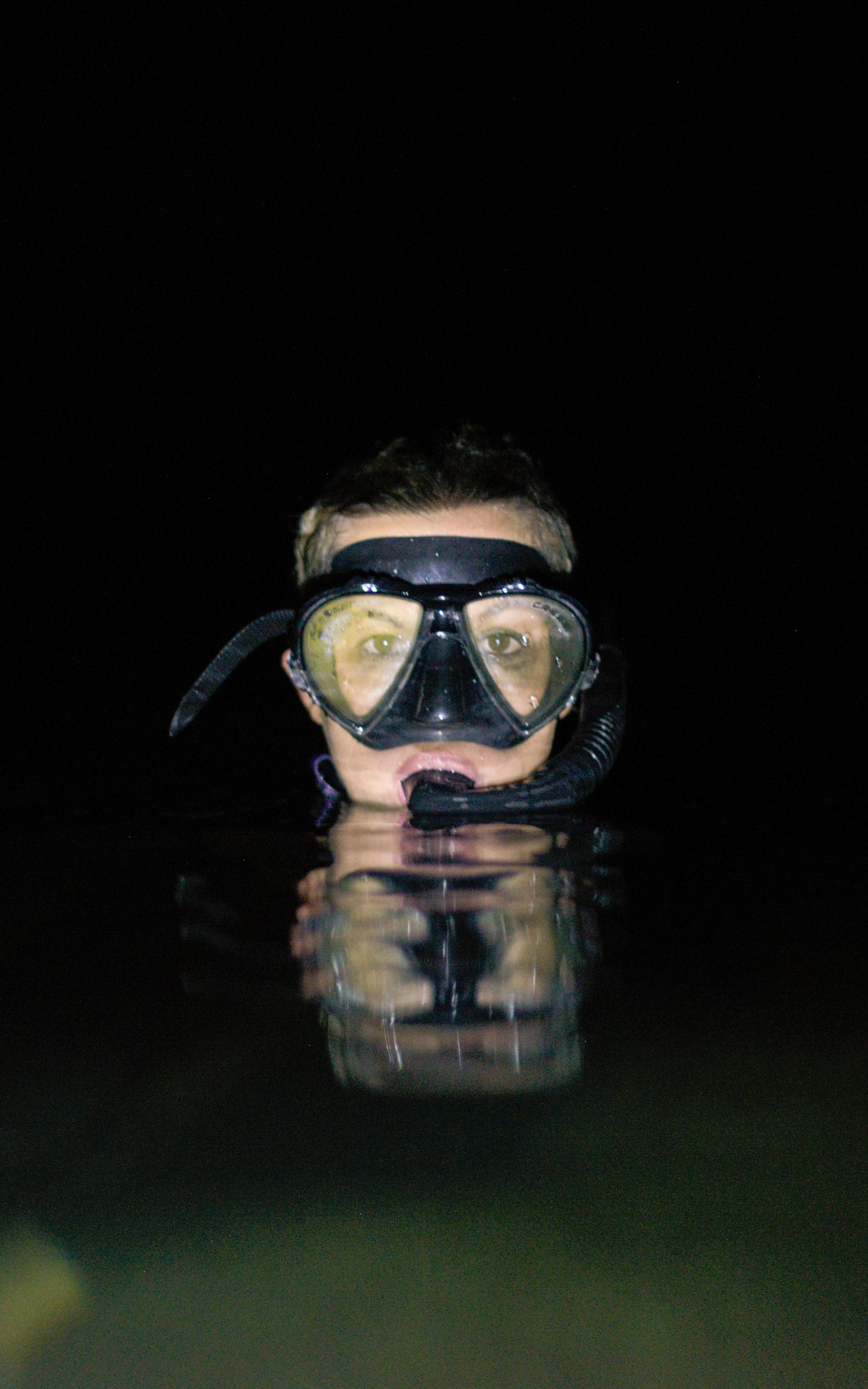 Woman in the sea at night wearing a snorkeling mask