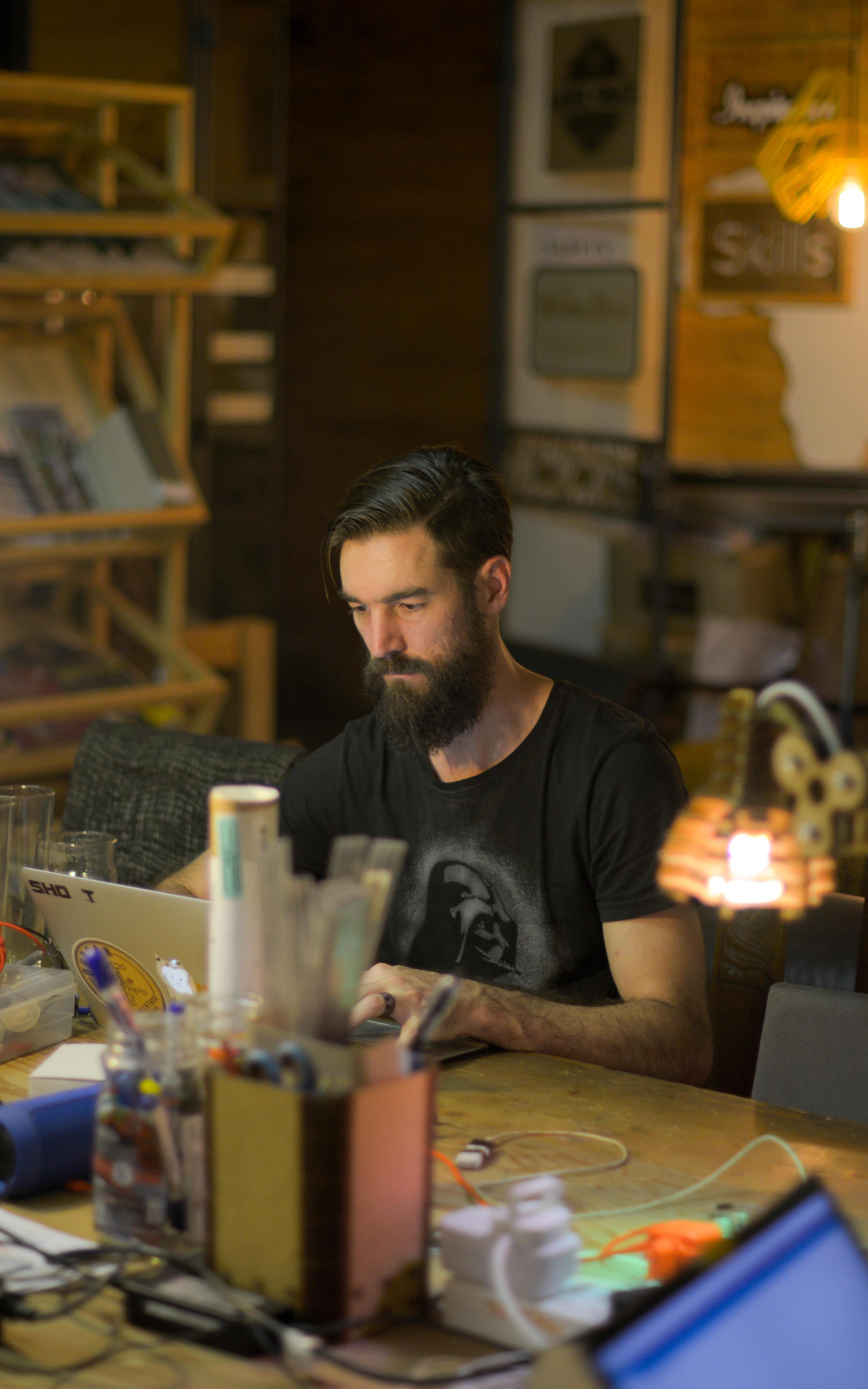 Man sits at a desk surrounded by different lamps