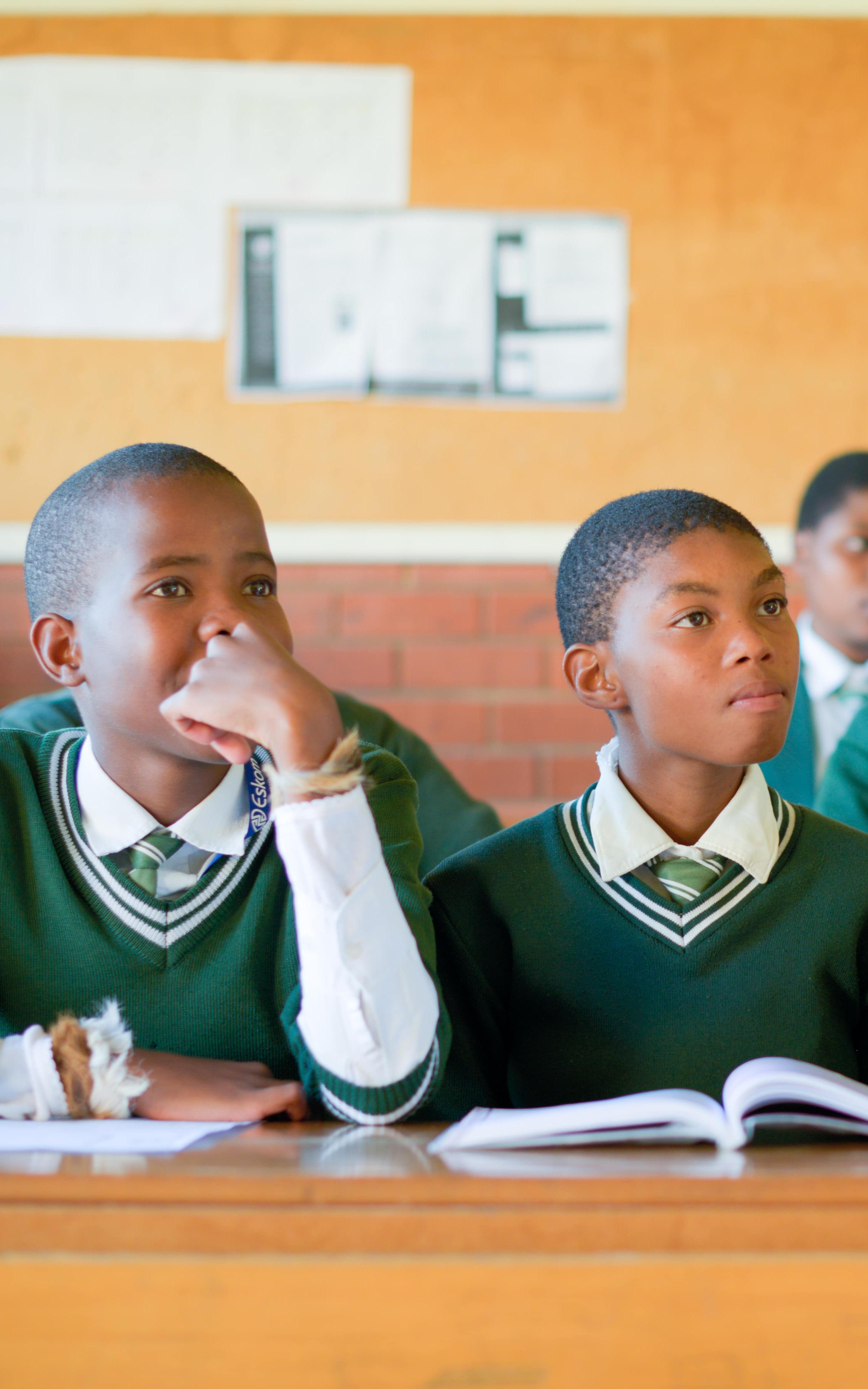 Boys in school uniform sit in a classroom