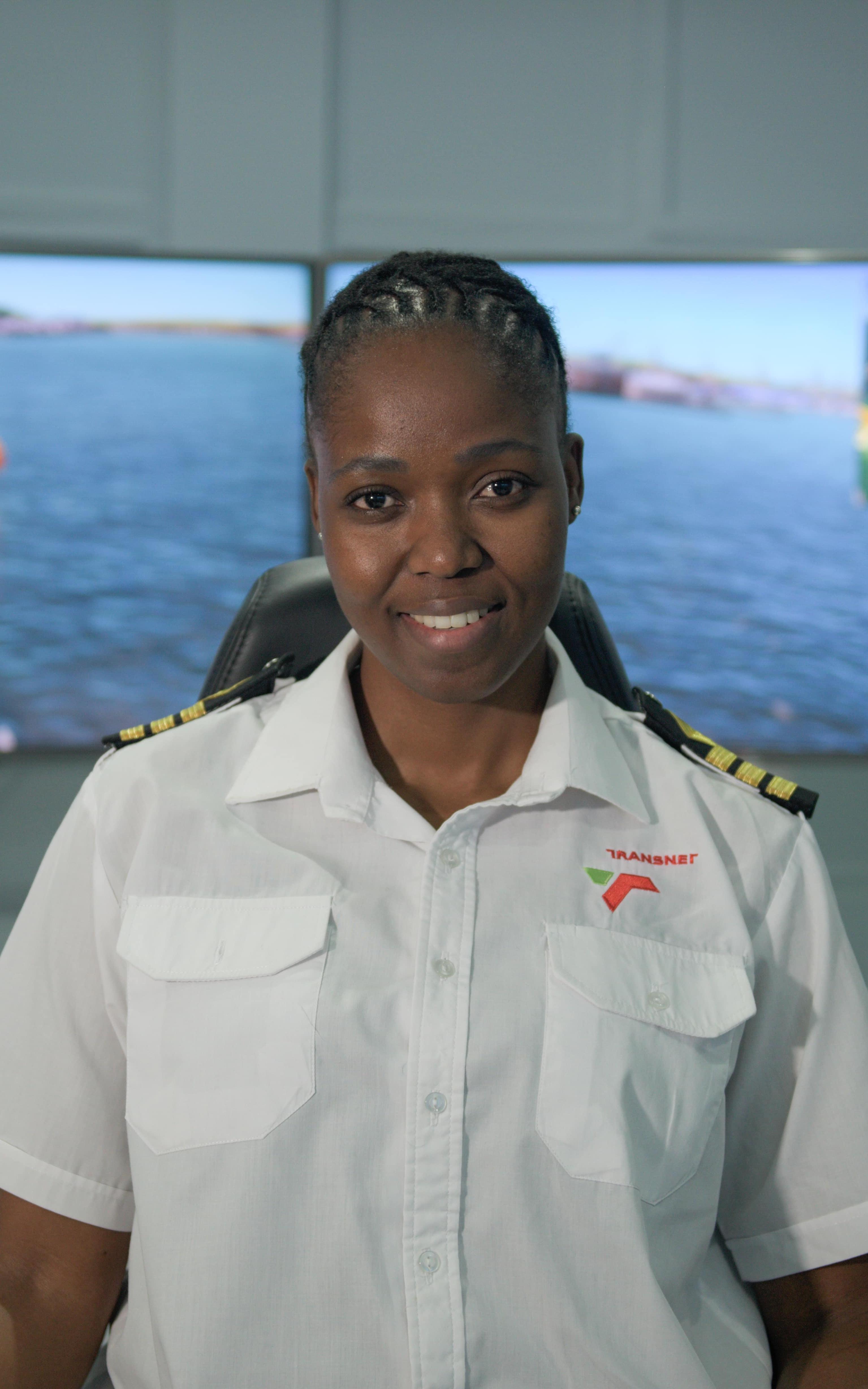 Woman smiles wearing a sailing uniform in front of sailing equipment