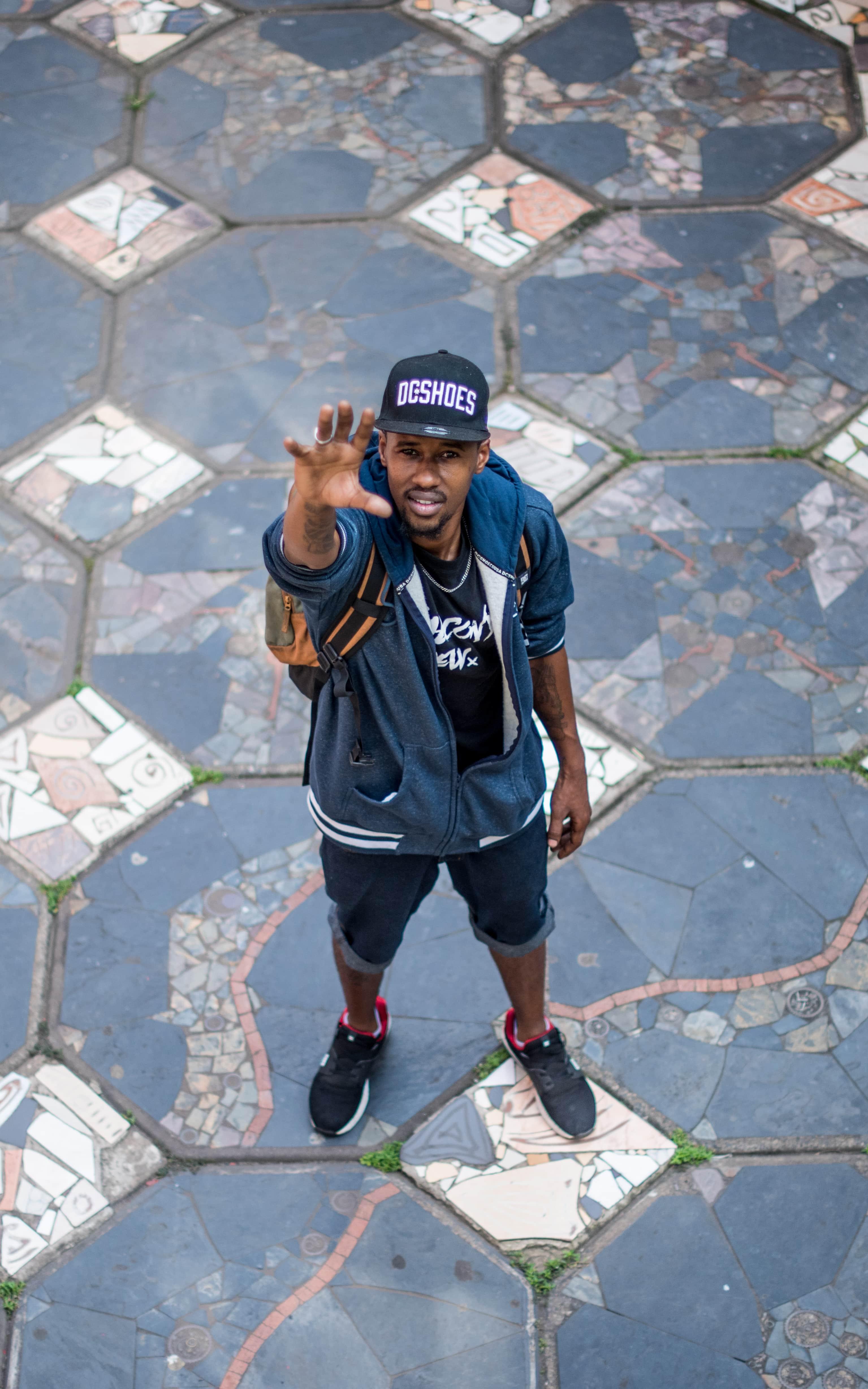 Black drummer reaching up towards camera.