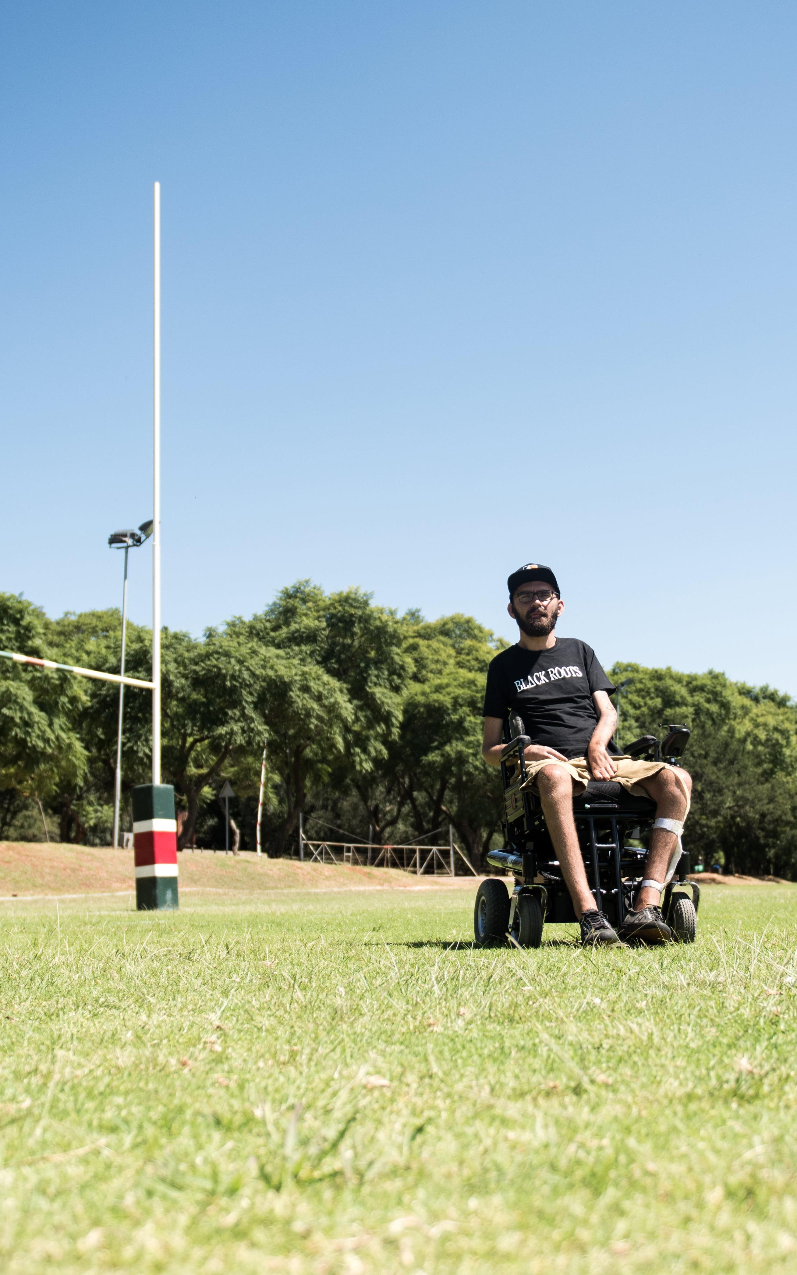 Man sits in a wheelchair on a rugby field