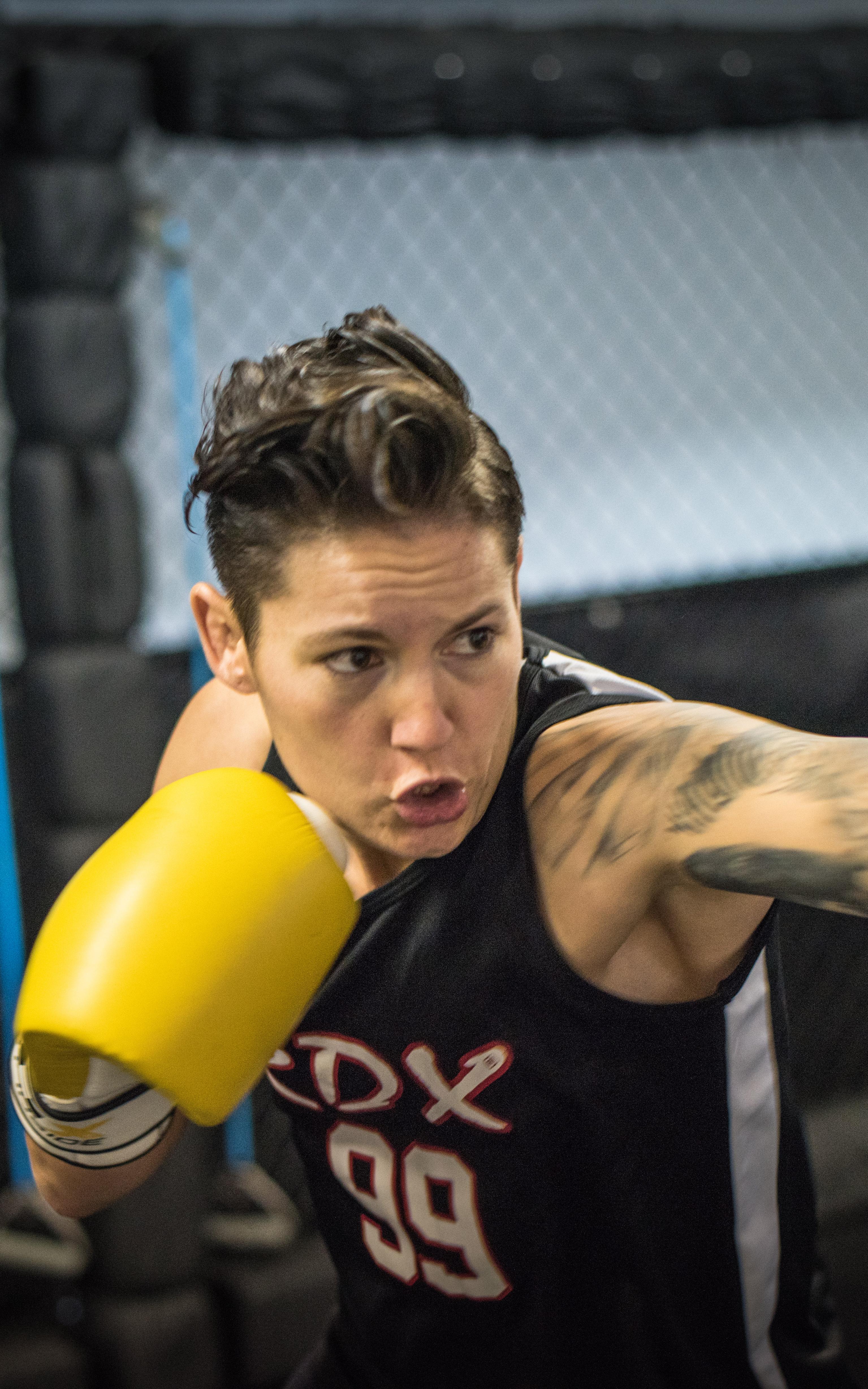 Woman wearing boxing gloves is aiming her glove at a punching bag