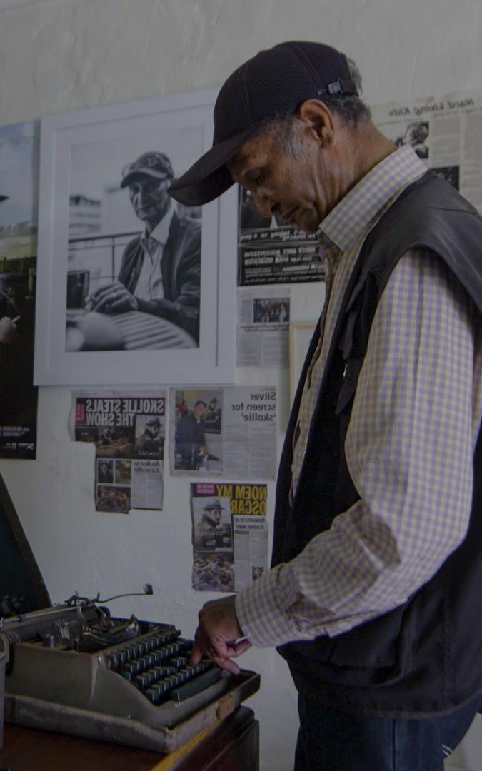 man standing by typewriter
