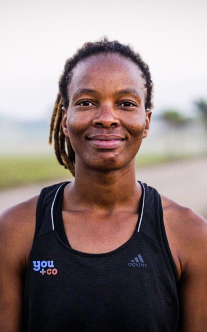 Black woman wearing running clothes is smiling at the camera